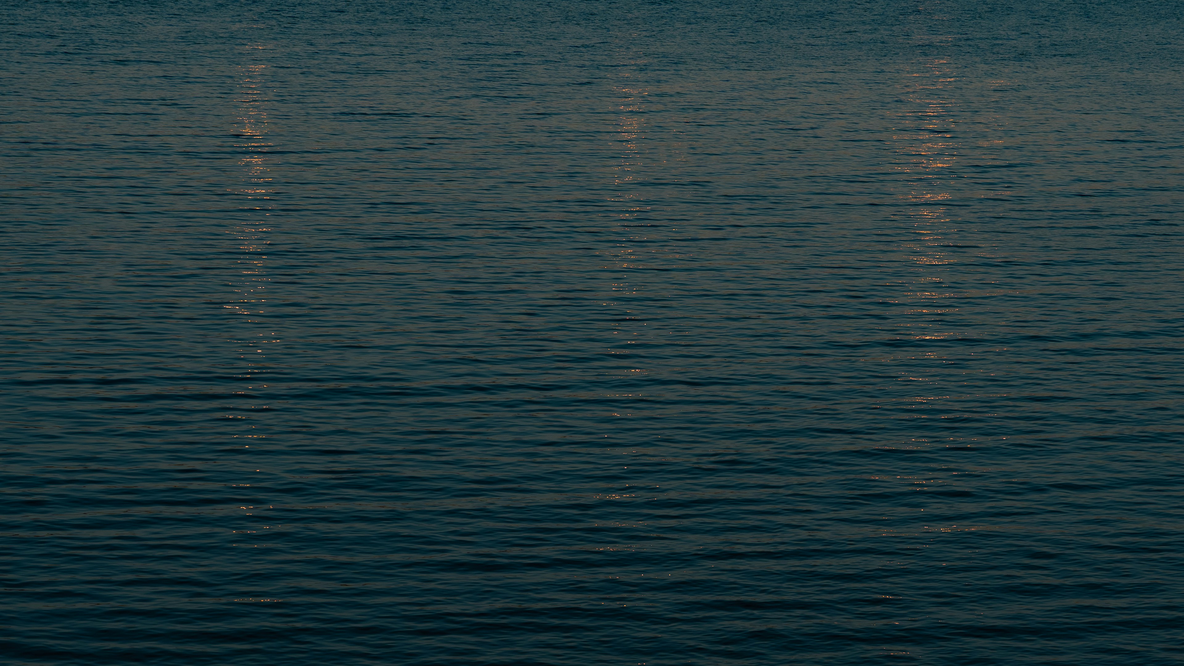Dark blue water with three vertical light reflections