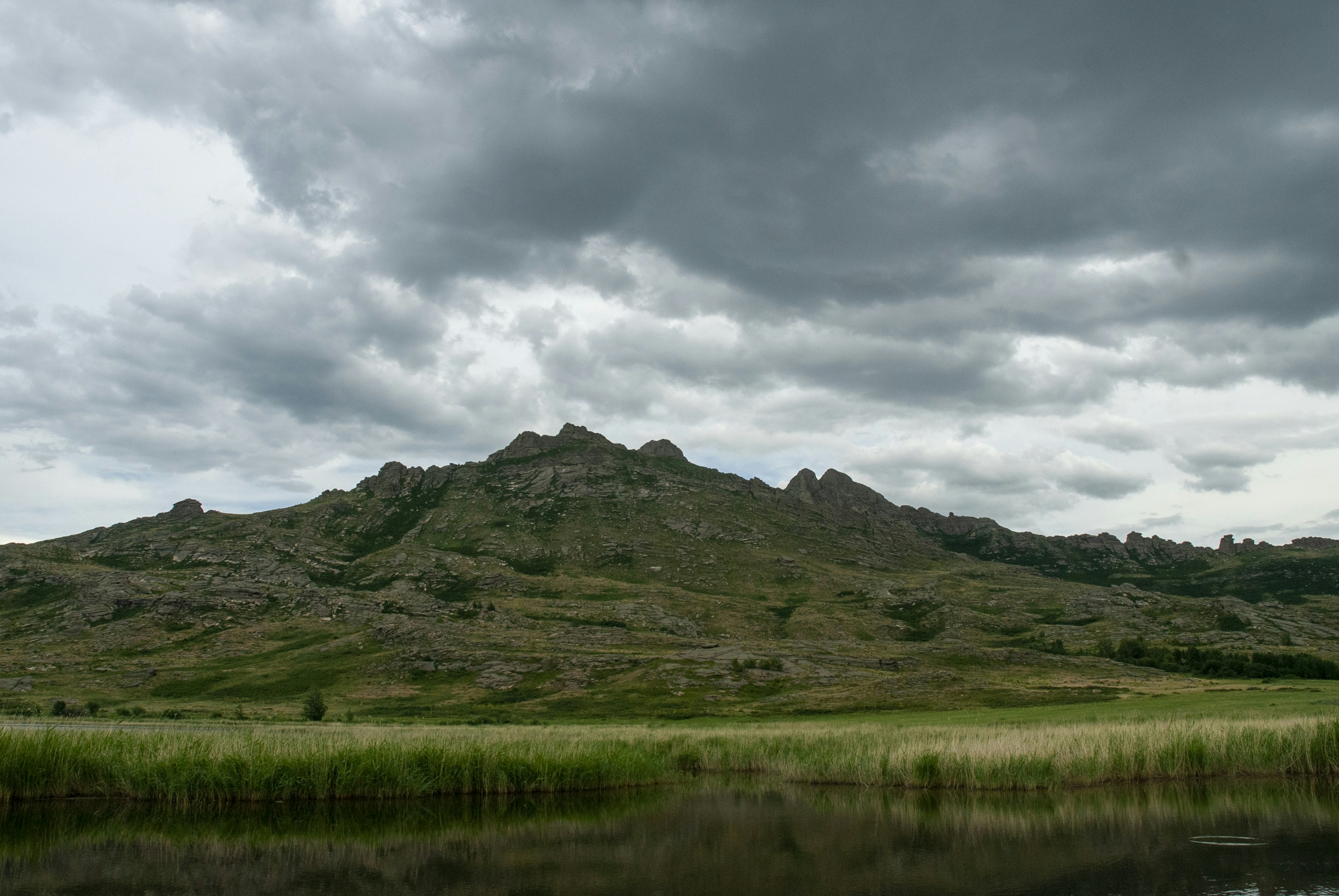 Rocky mountains with dry grass under a cloudy sky