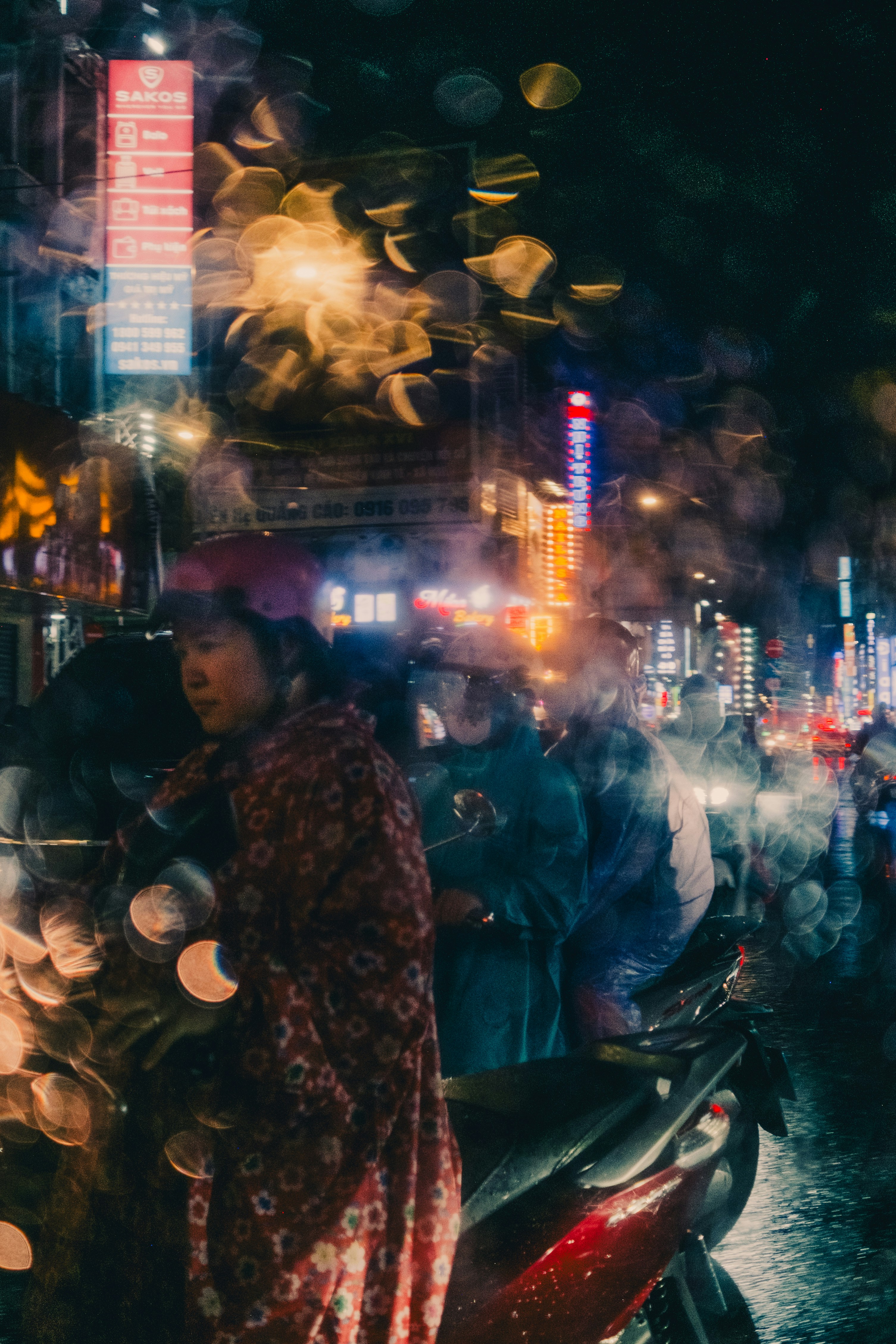 Rainy night in a city with people and blurred lights.