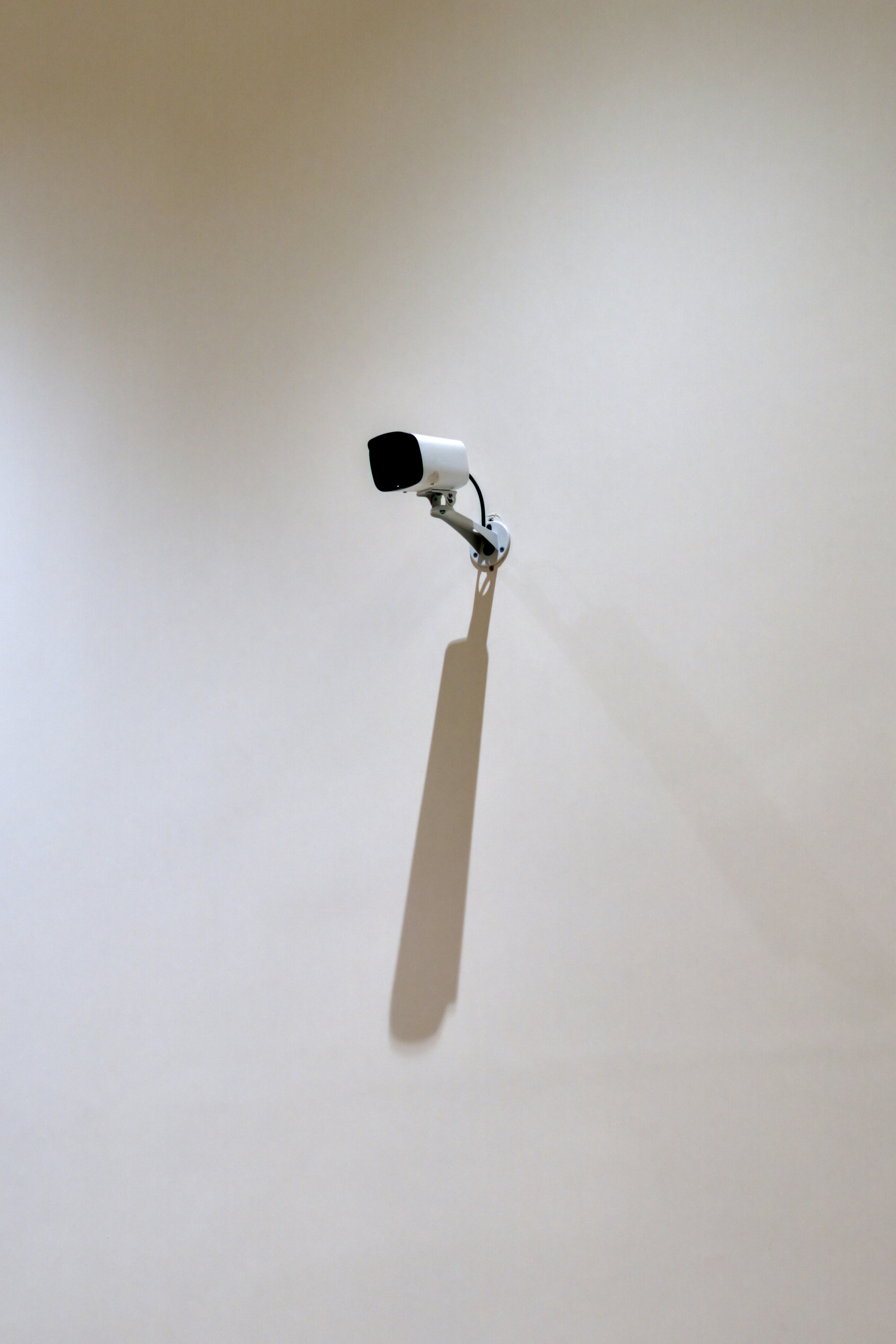 White security camera casting a long shadow on a wall.