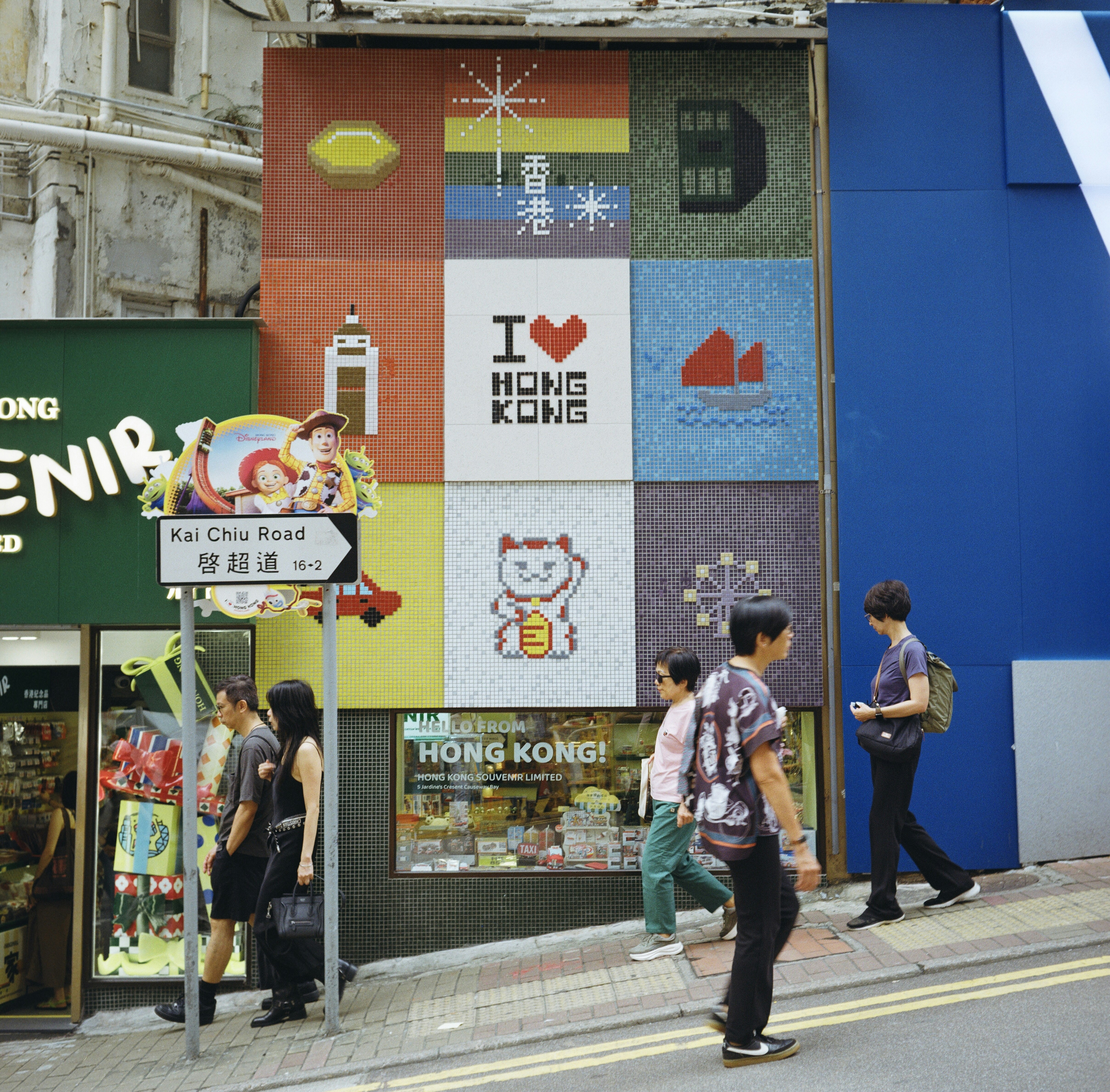 People walk past a colorful hong kong mosaic art installation.