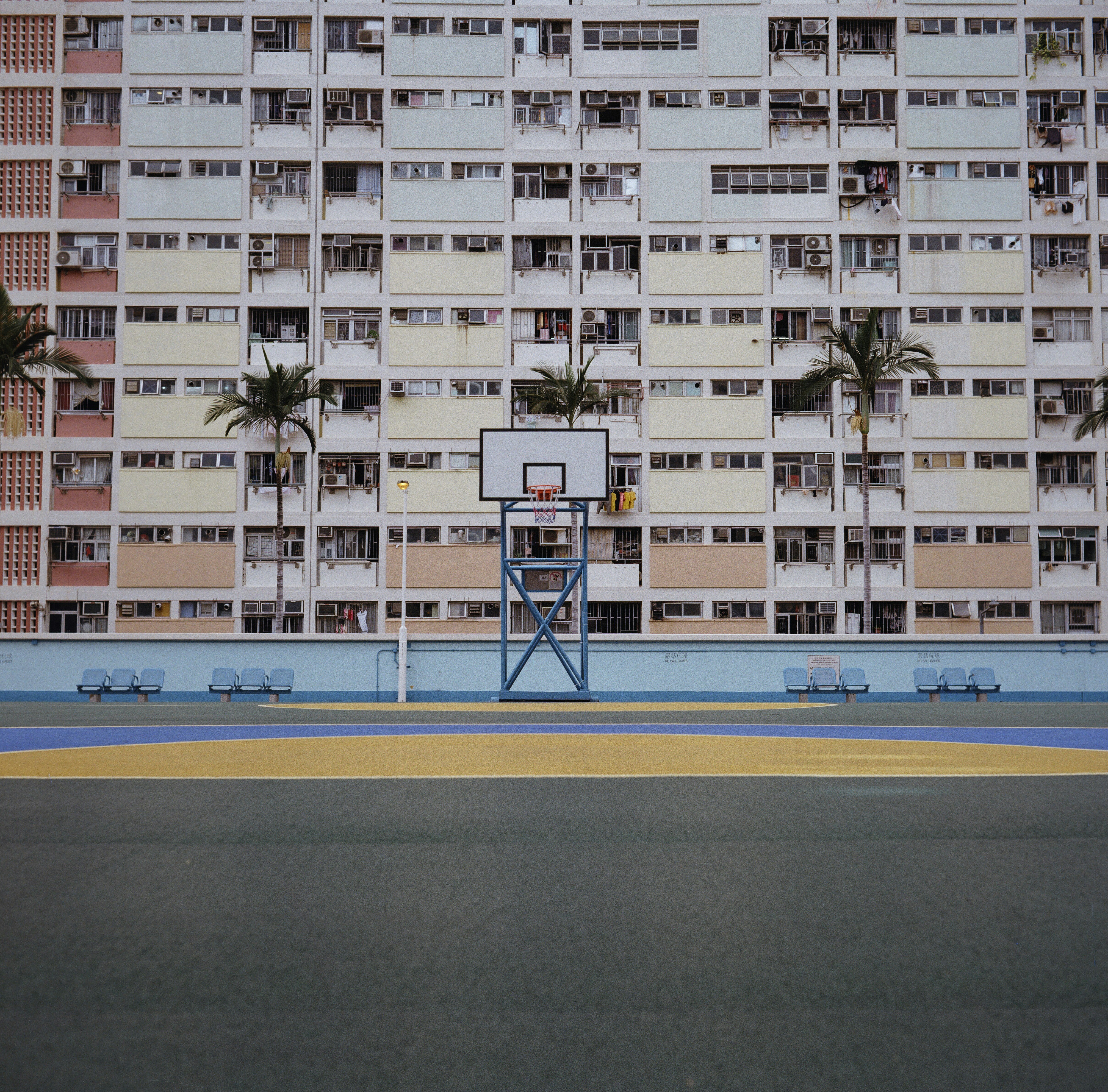 Basketball court in front of a colorful apartment building.
