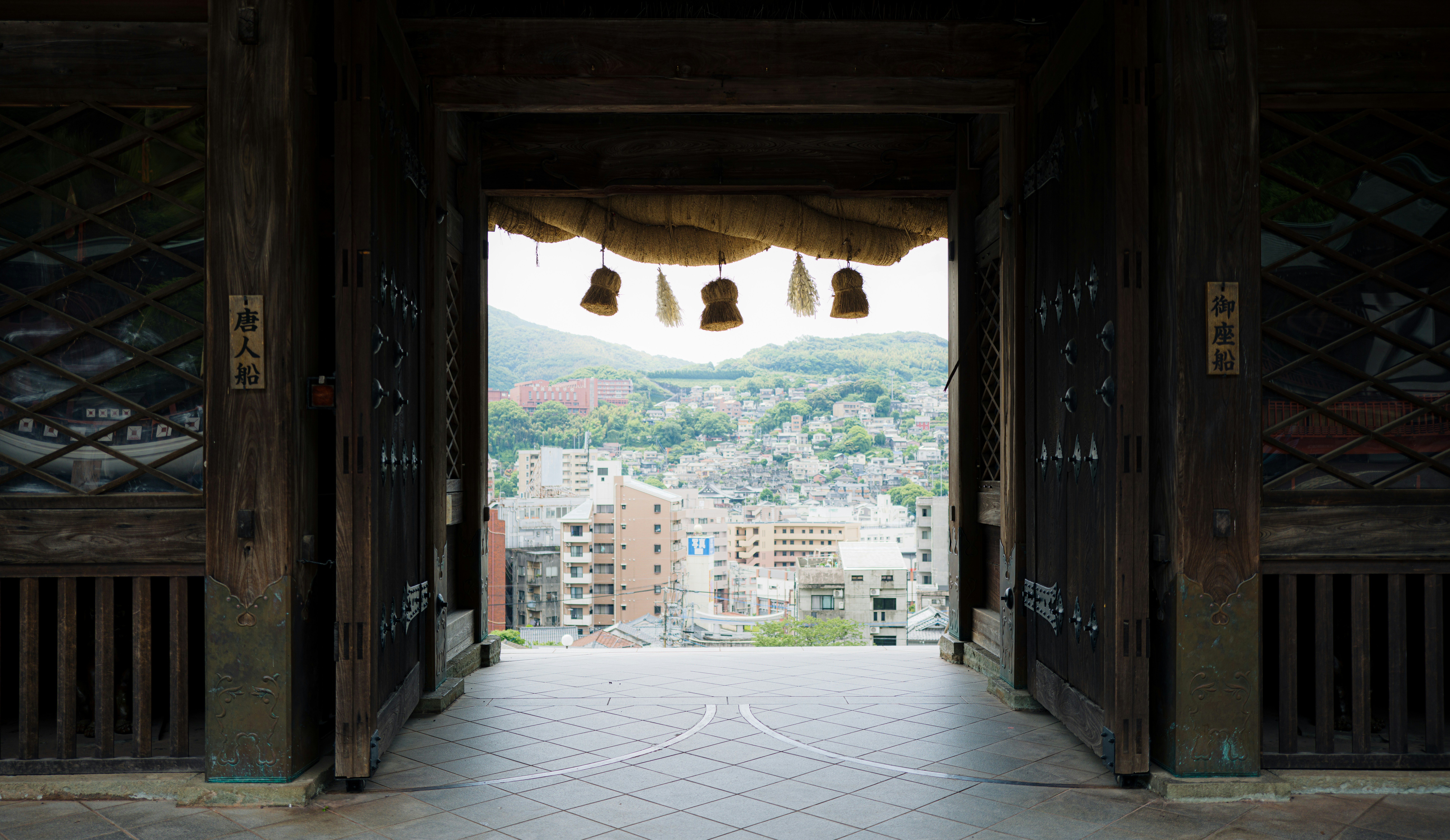 Das traditionelle japanische Tor rahmt eine Stadtansicht mit fernen Bergen ein.