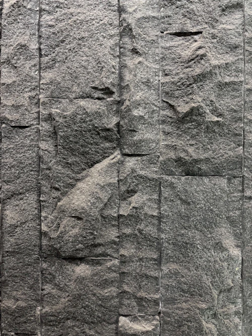 Parede revestida com placas de pedra escura em textura vertical