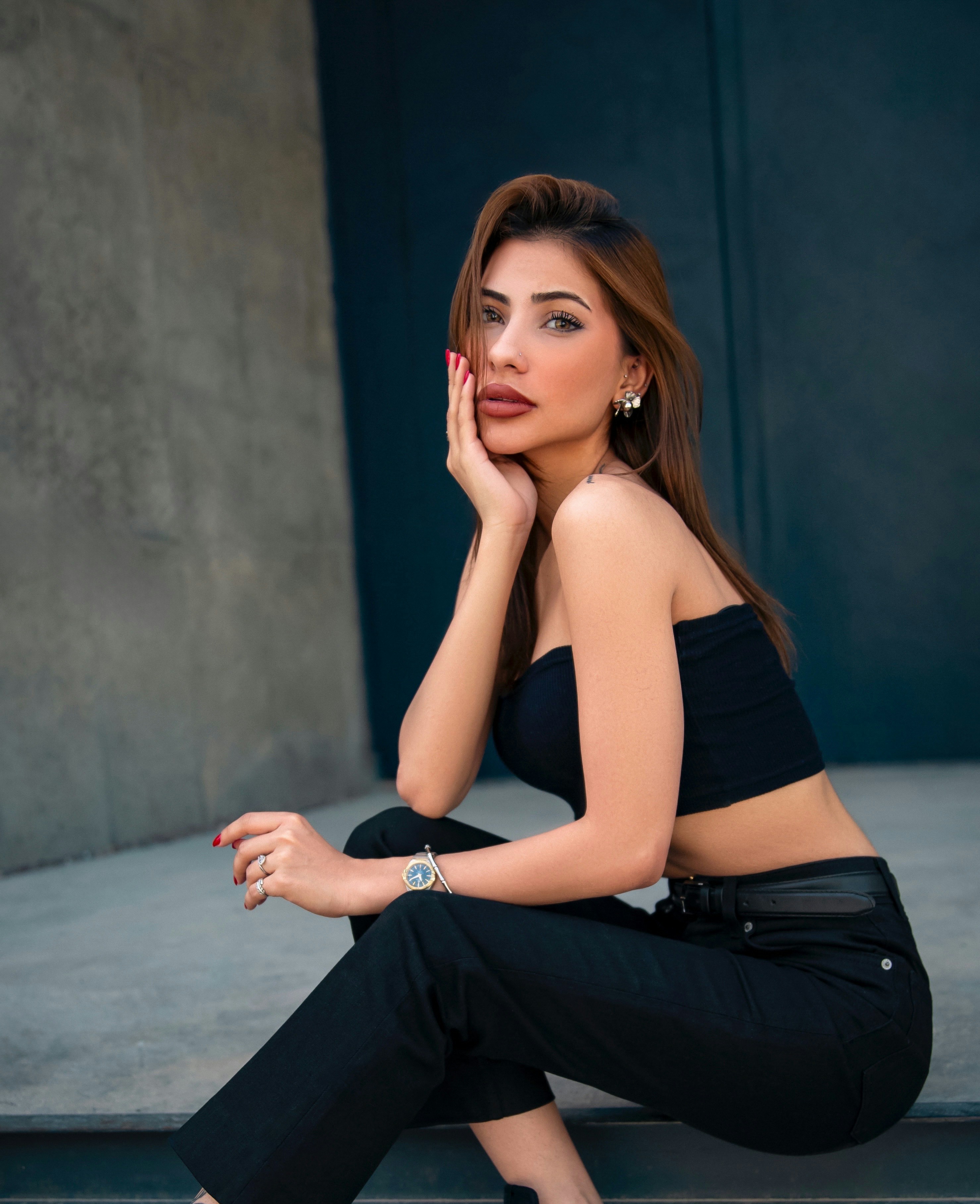Femme stylée en haut noir et pantalon assise.