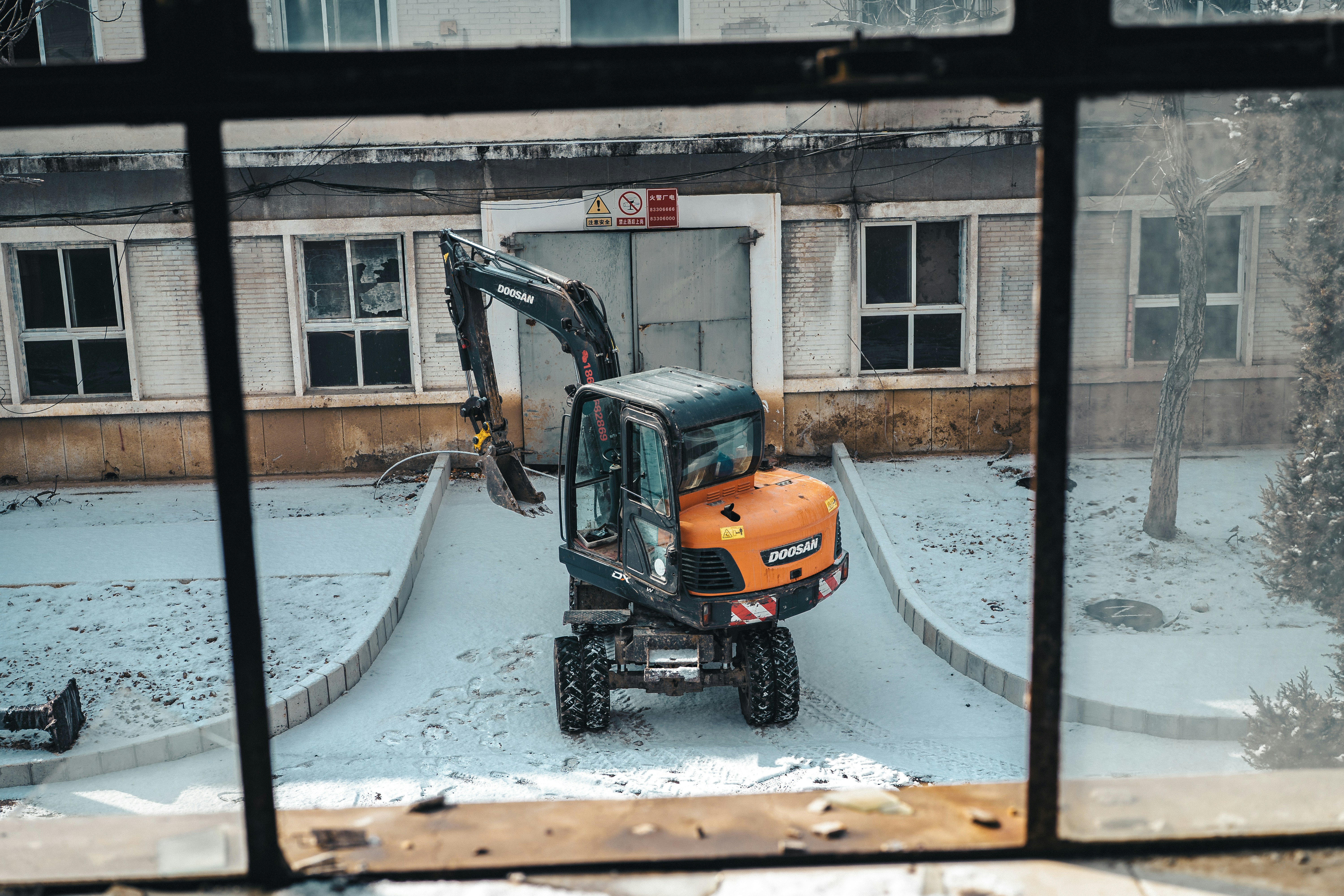 Orange excavator parked outside a building.