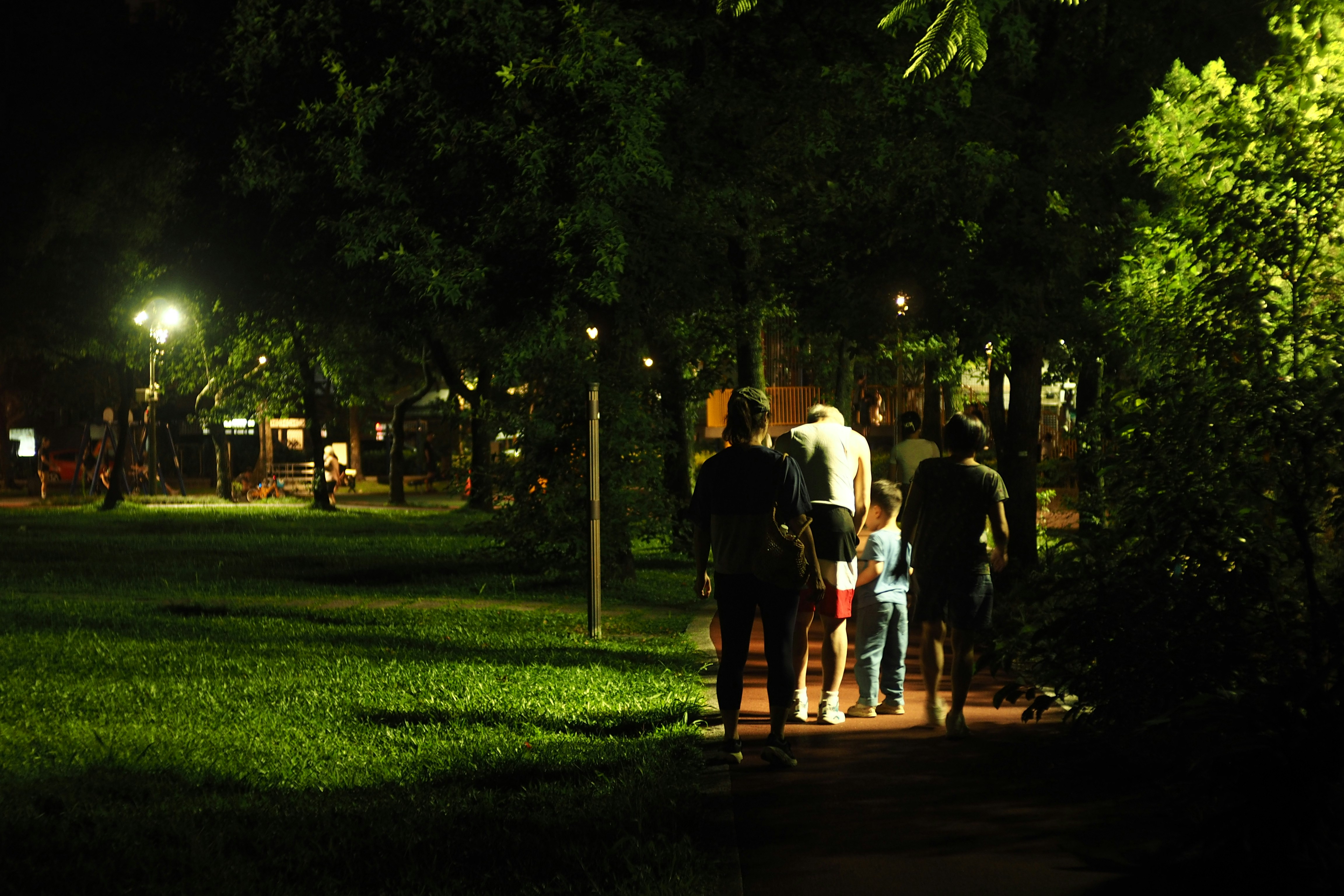 夜の暗い公園を街灯のまま歩く人たち。