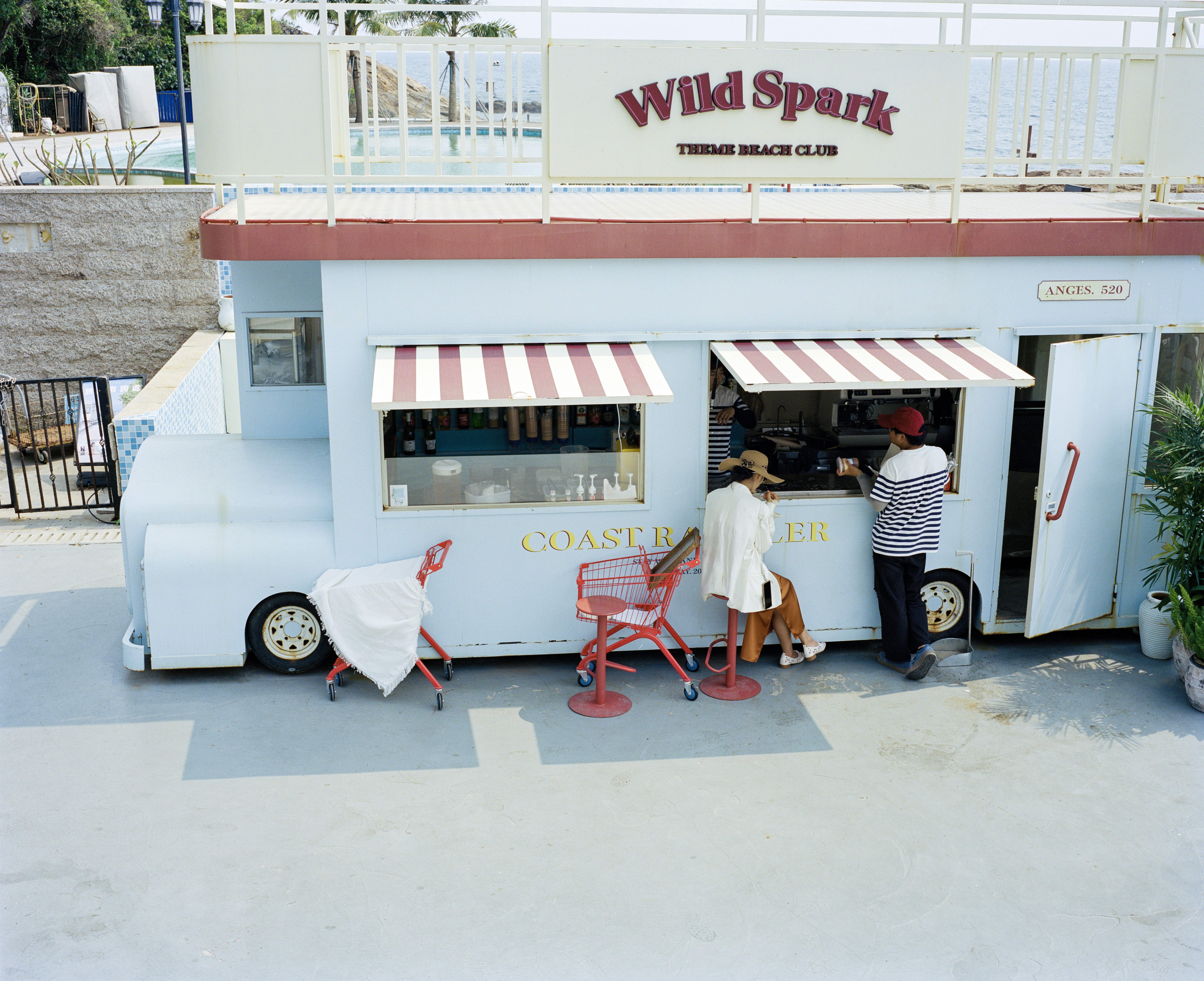 Blue food truck with customers at wild spark beach club.
