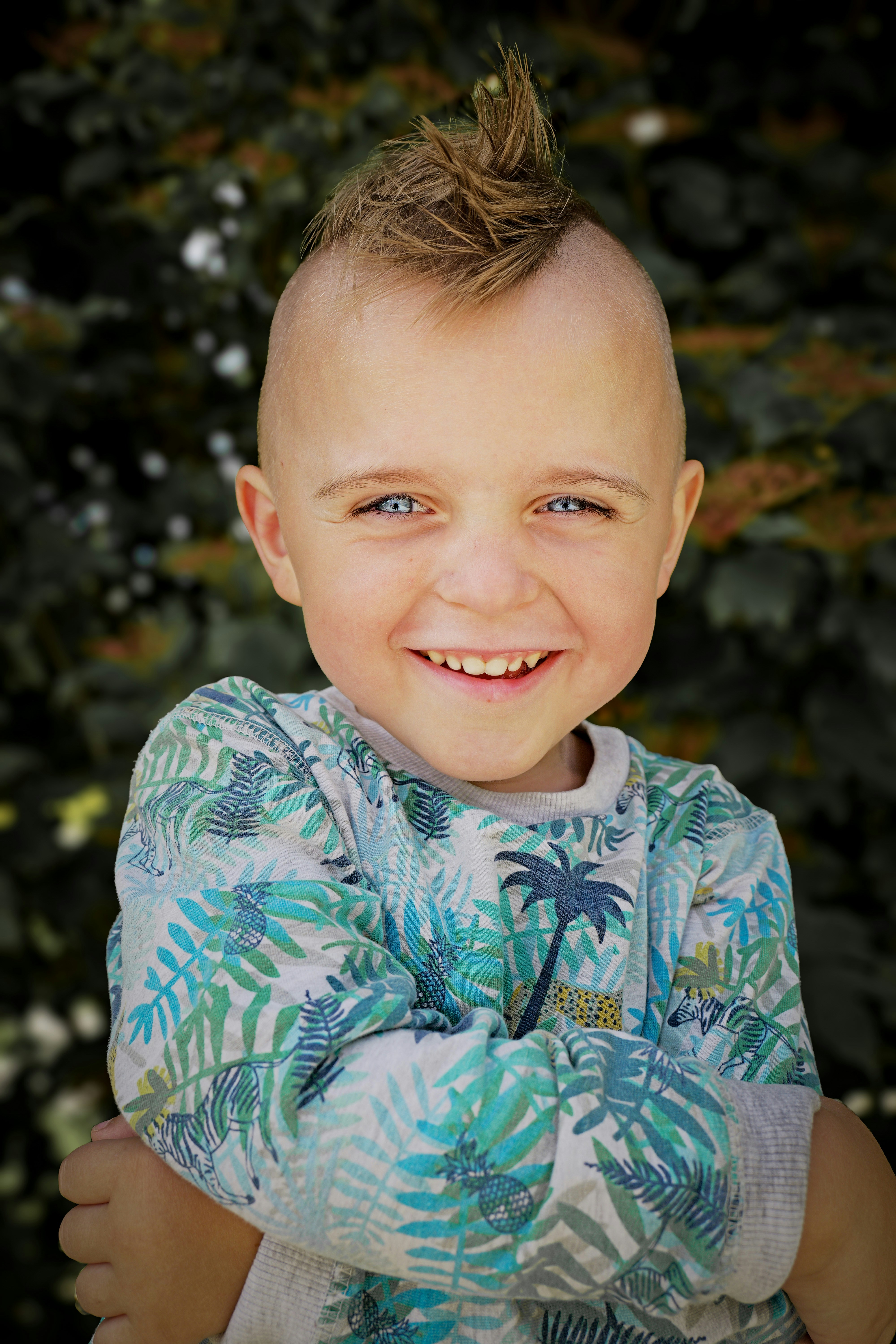 Smiling boy with blue eyes and a mohawk haircut.