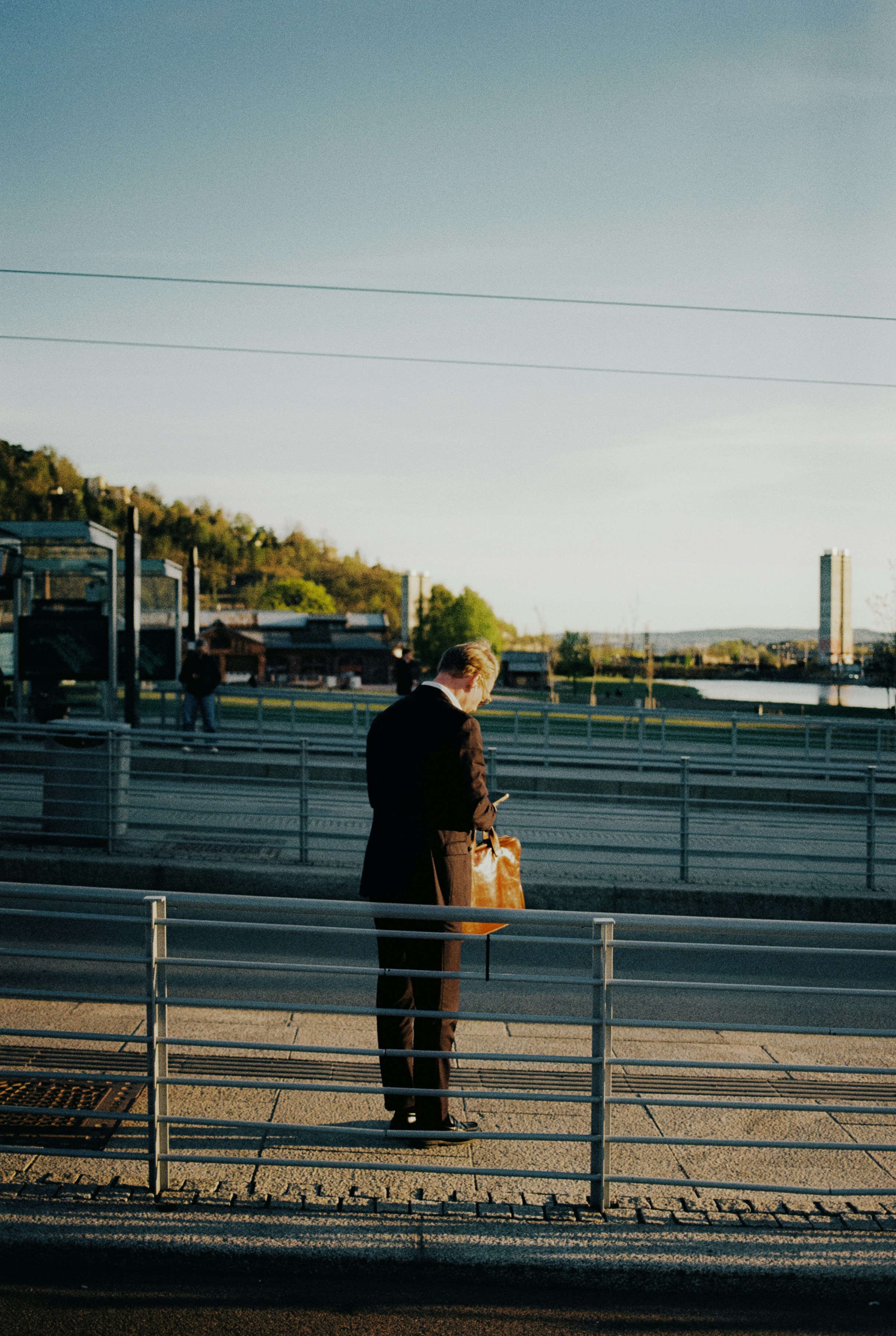 A businessman checks his phone while waiting on a platform