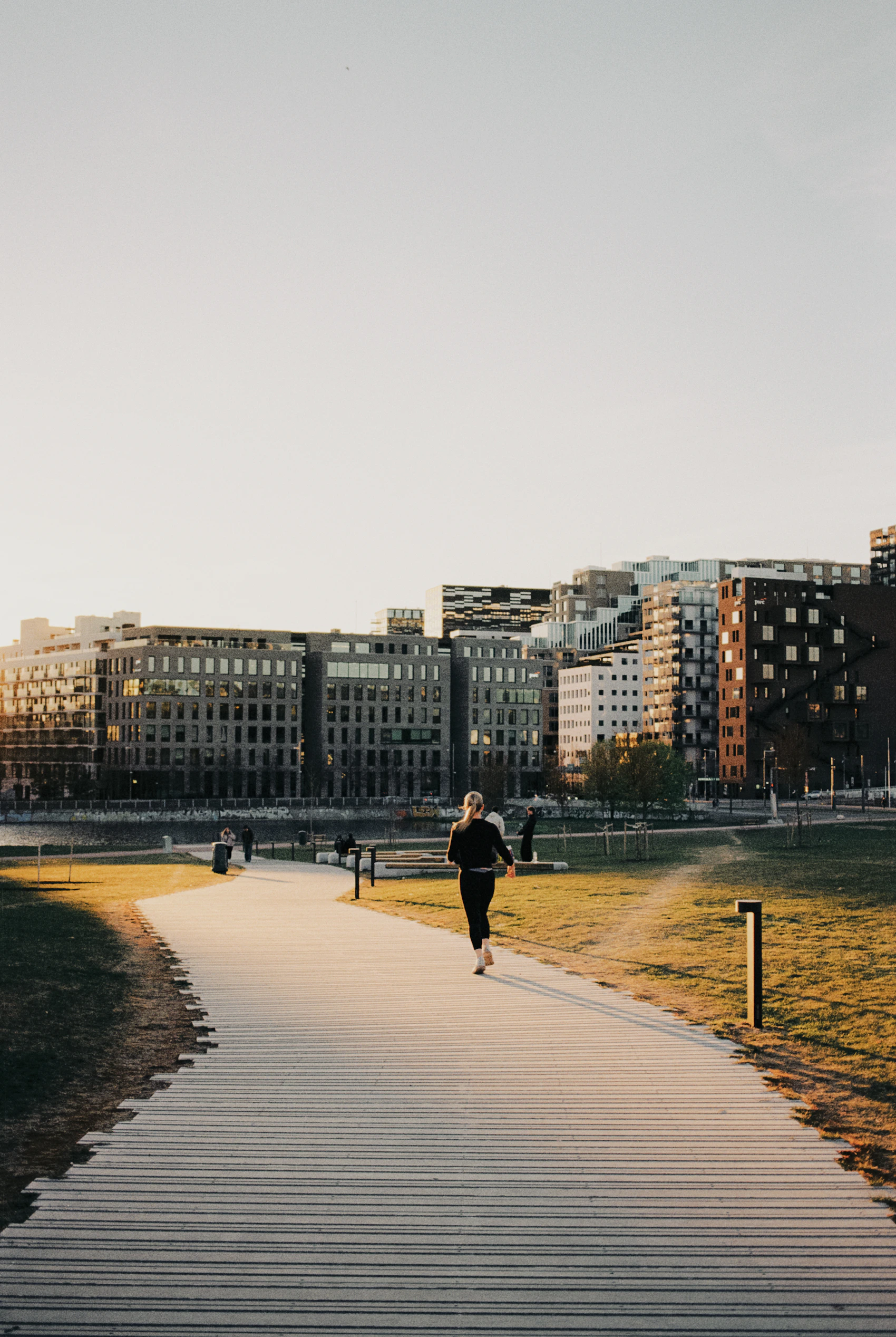 Runner moving along a city park path at sunset