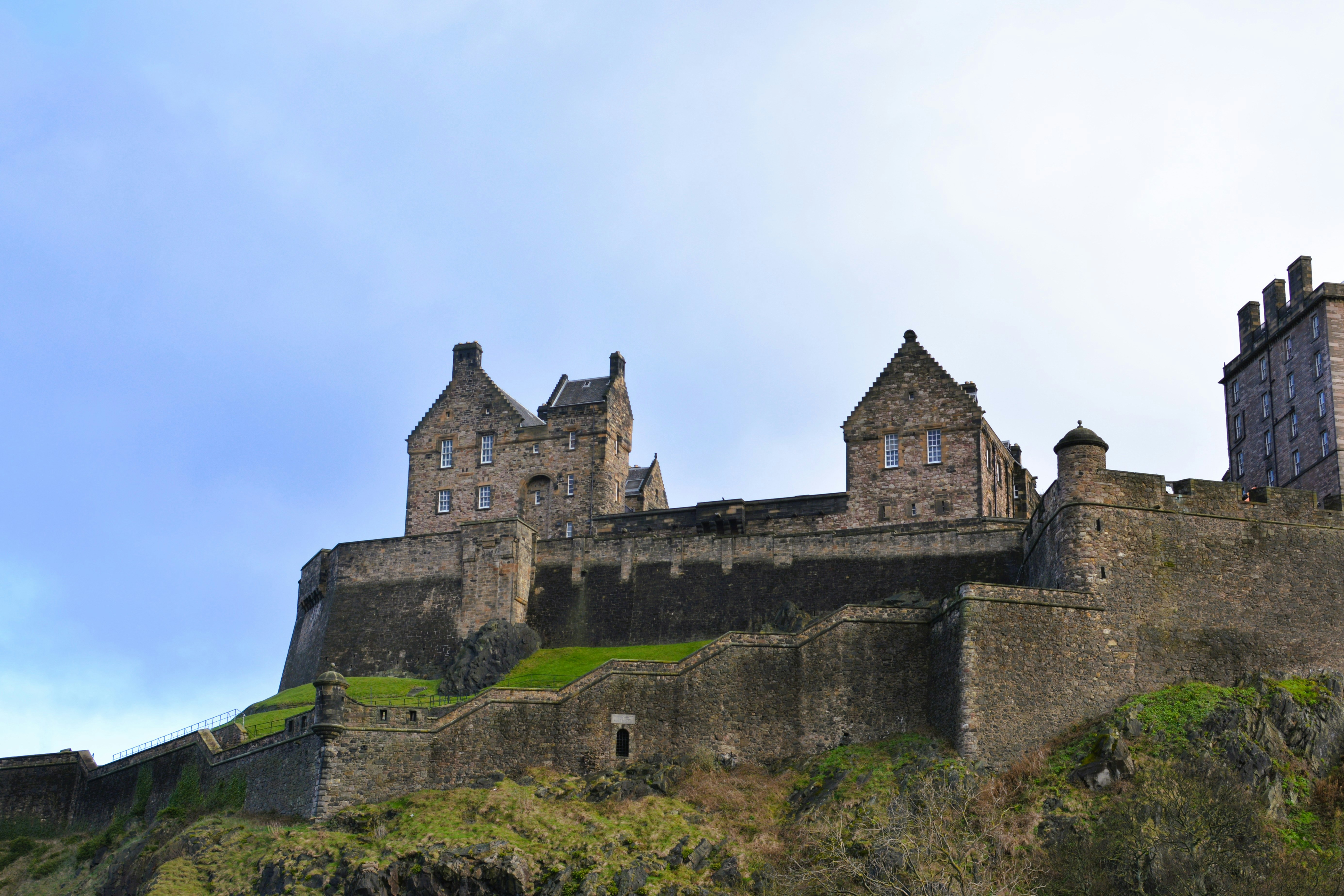 A historic stone castle stands on a green hill.