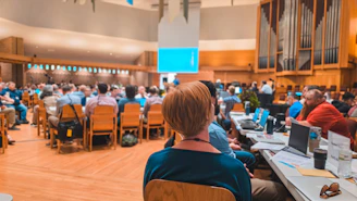 Audience gathered in a large hall for a presentation.