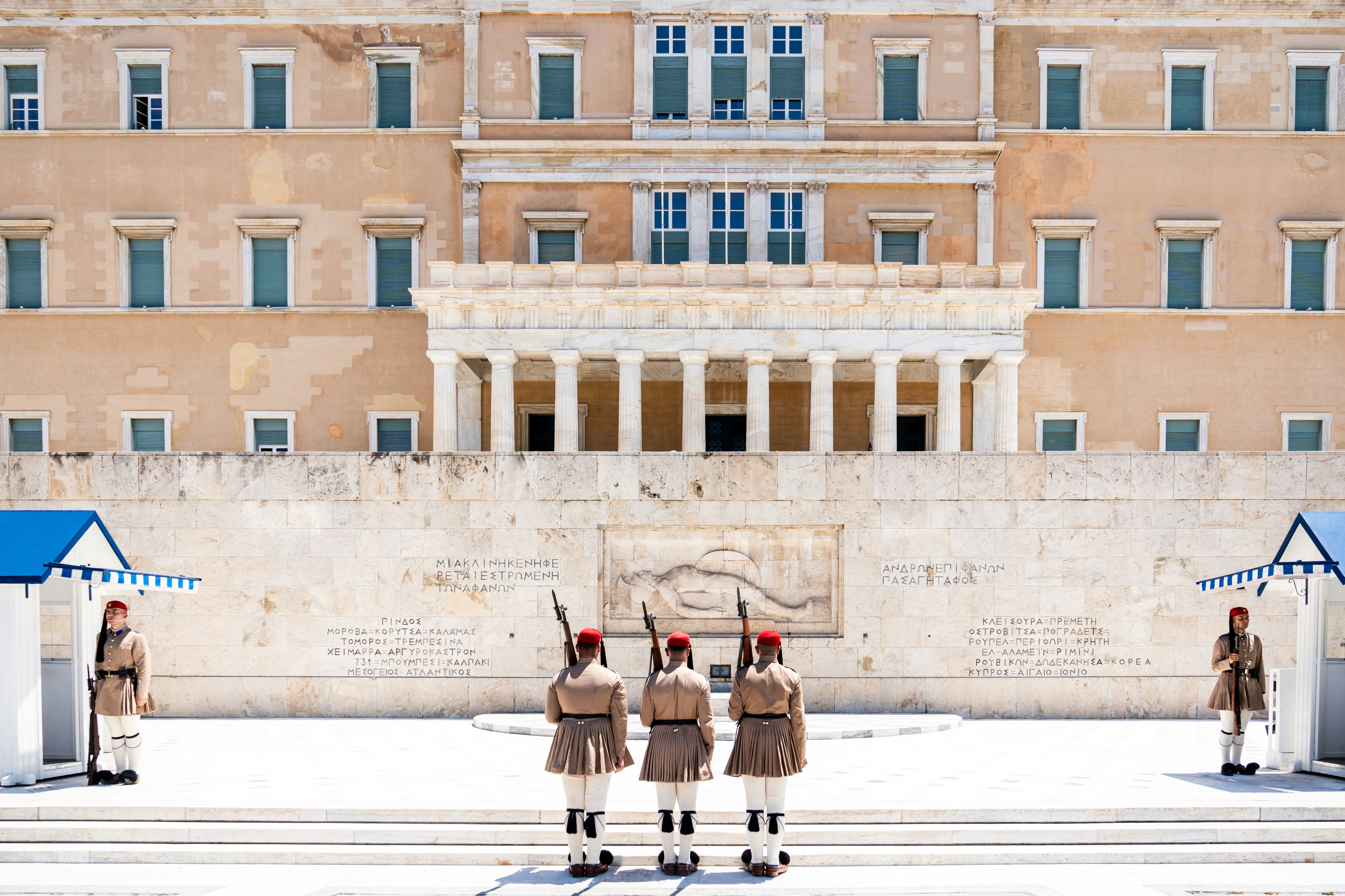 Three evzones guard the hellenic parliament building in athens