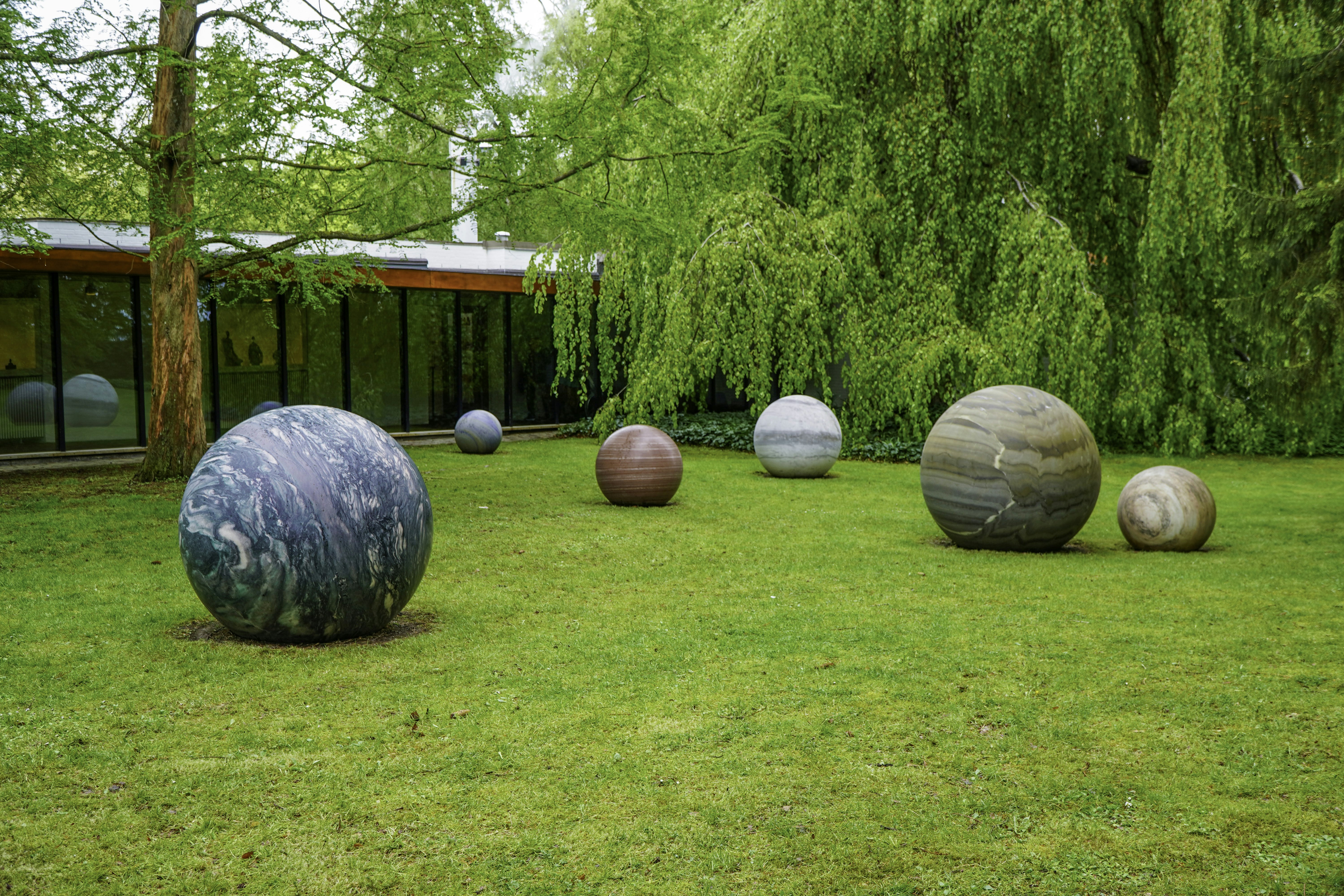 Various large stone spheres scattered on a green lawn.