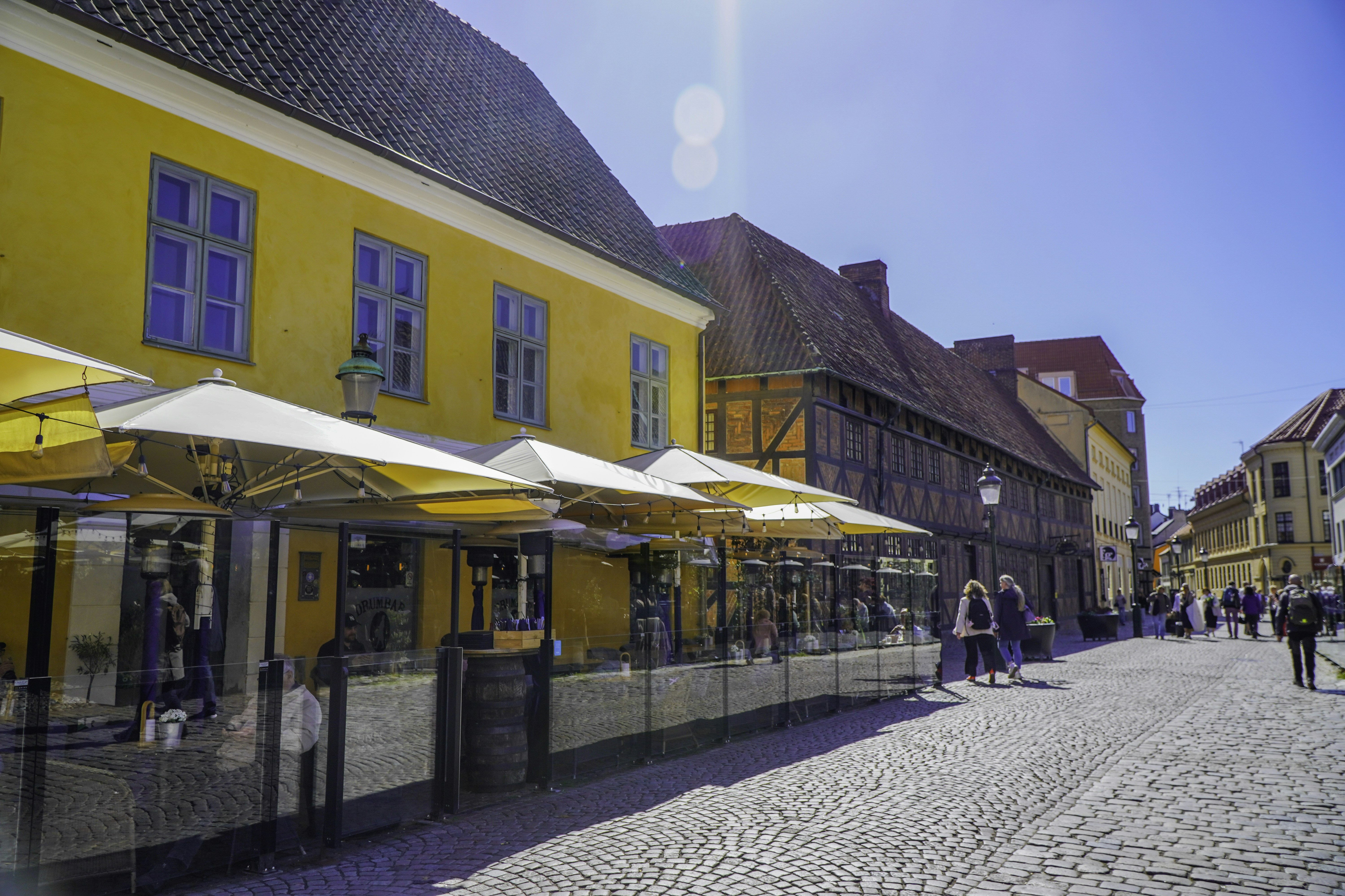 Vibrant street scene with yellow buildings and outdoor cafe seating.