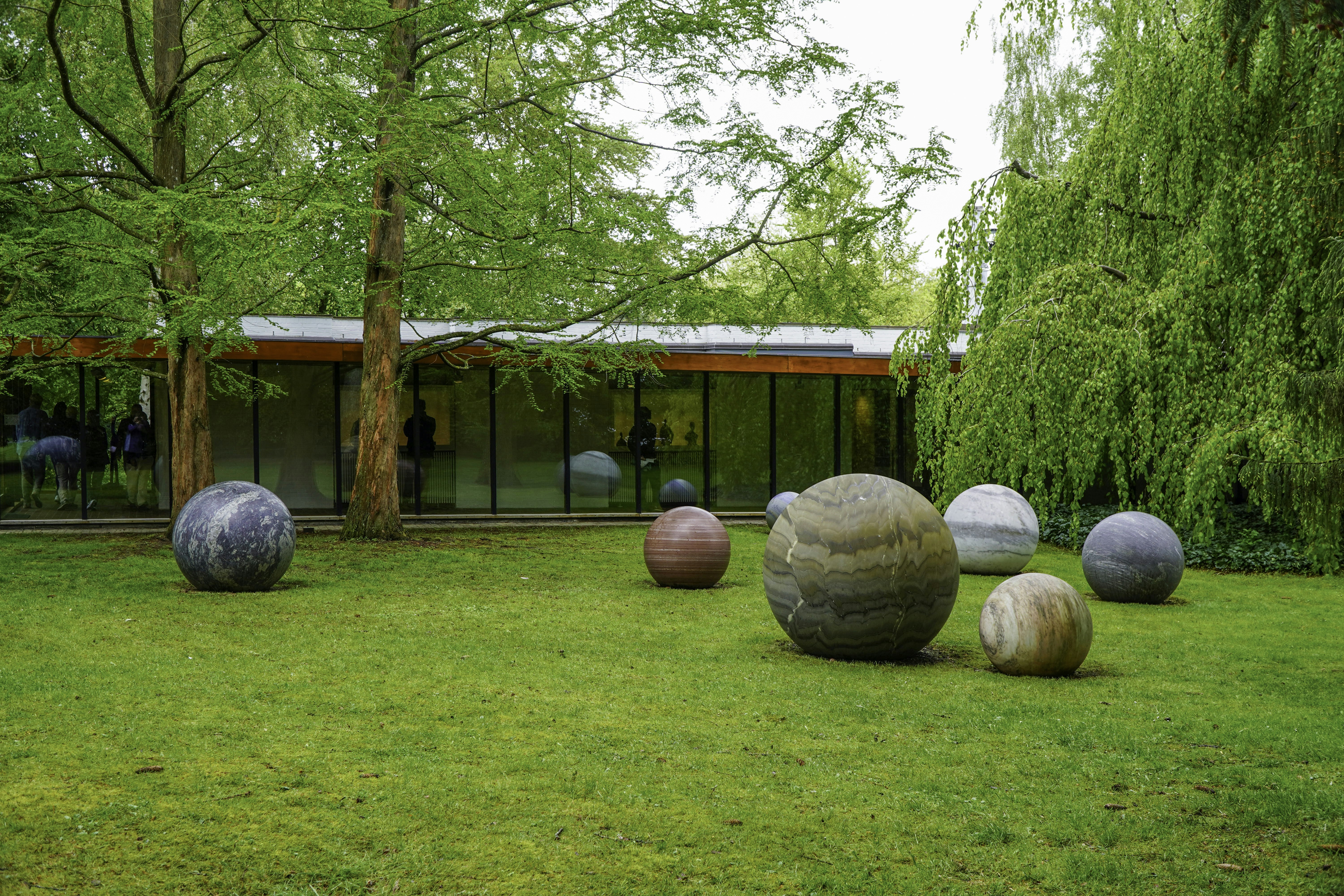 Modern building and spherical sculptures on a green lawn.