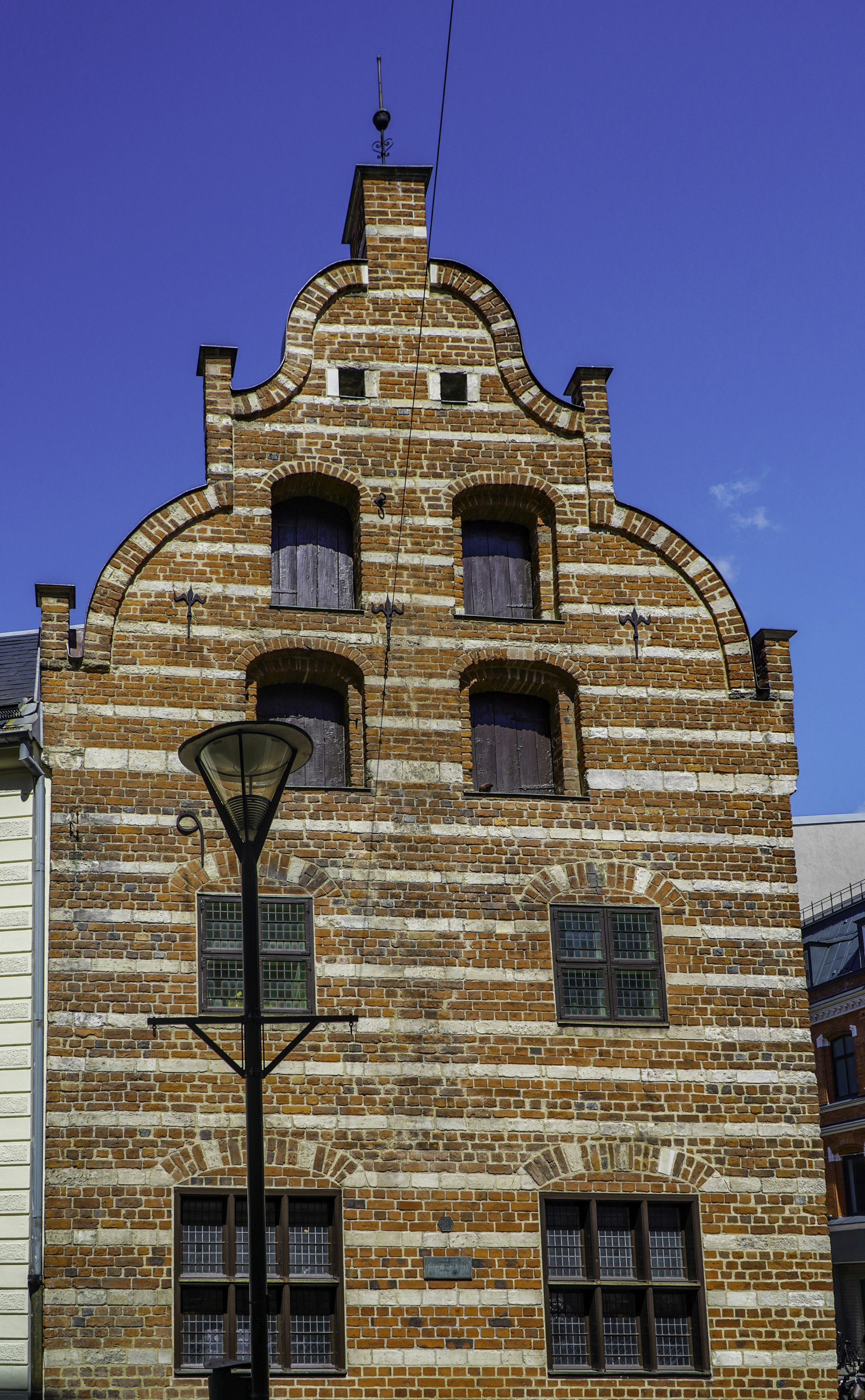 Old brick house with a curved gable and street lamp.