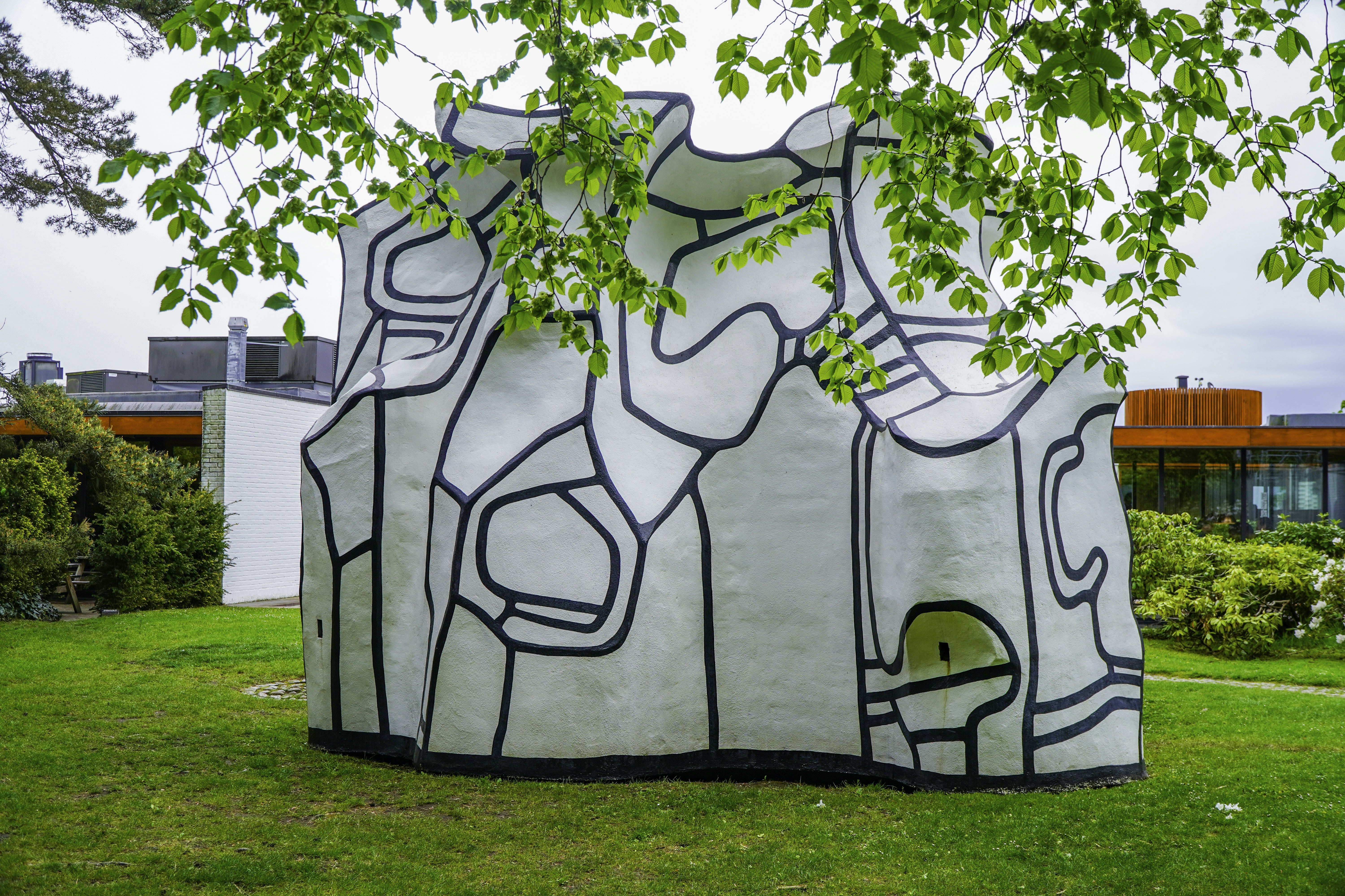 Abstract white sculpture with black lines on a green lawn.