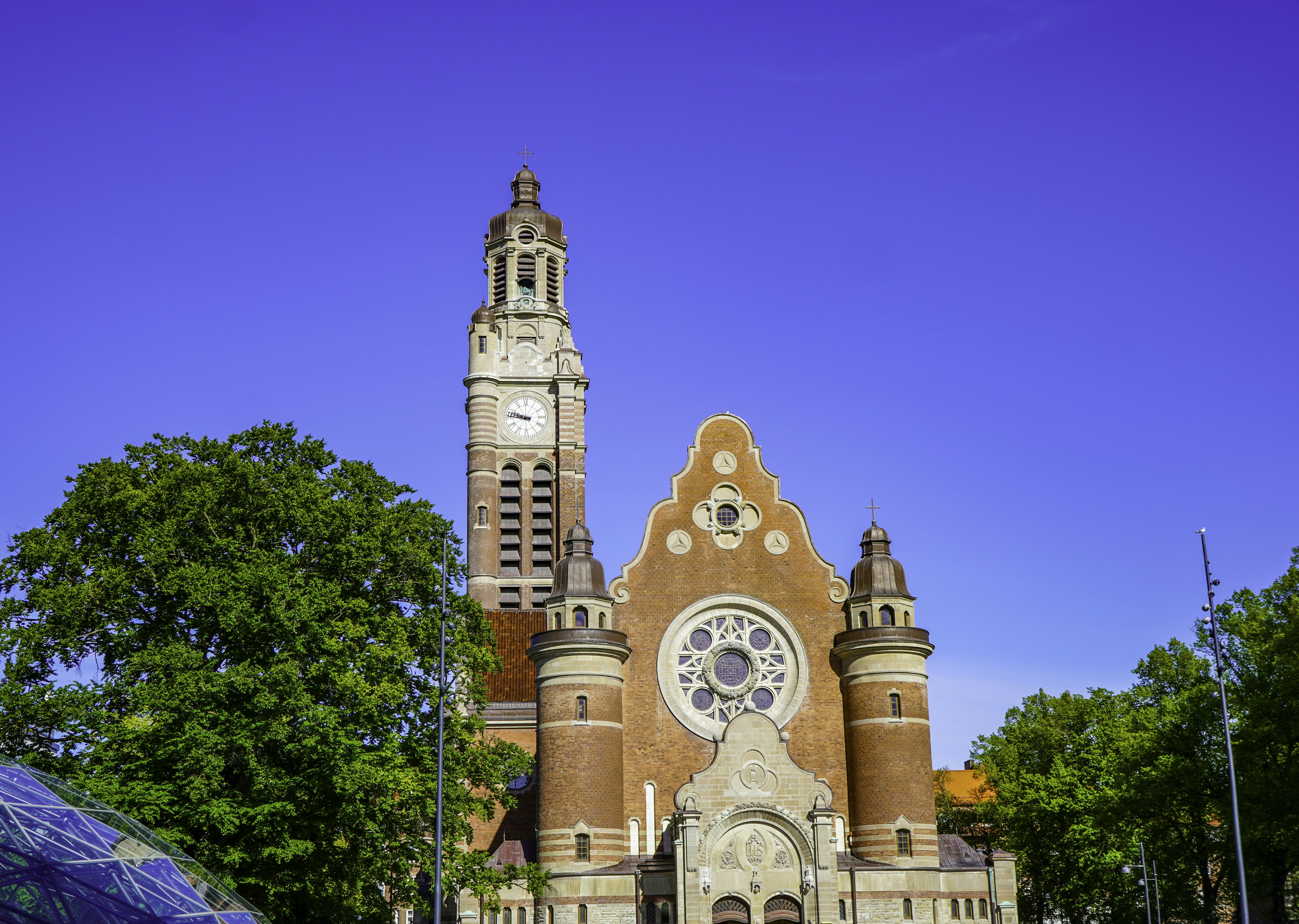 Large brick church with clock tower under clear blue sky.