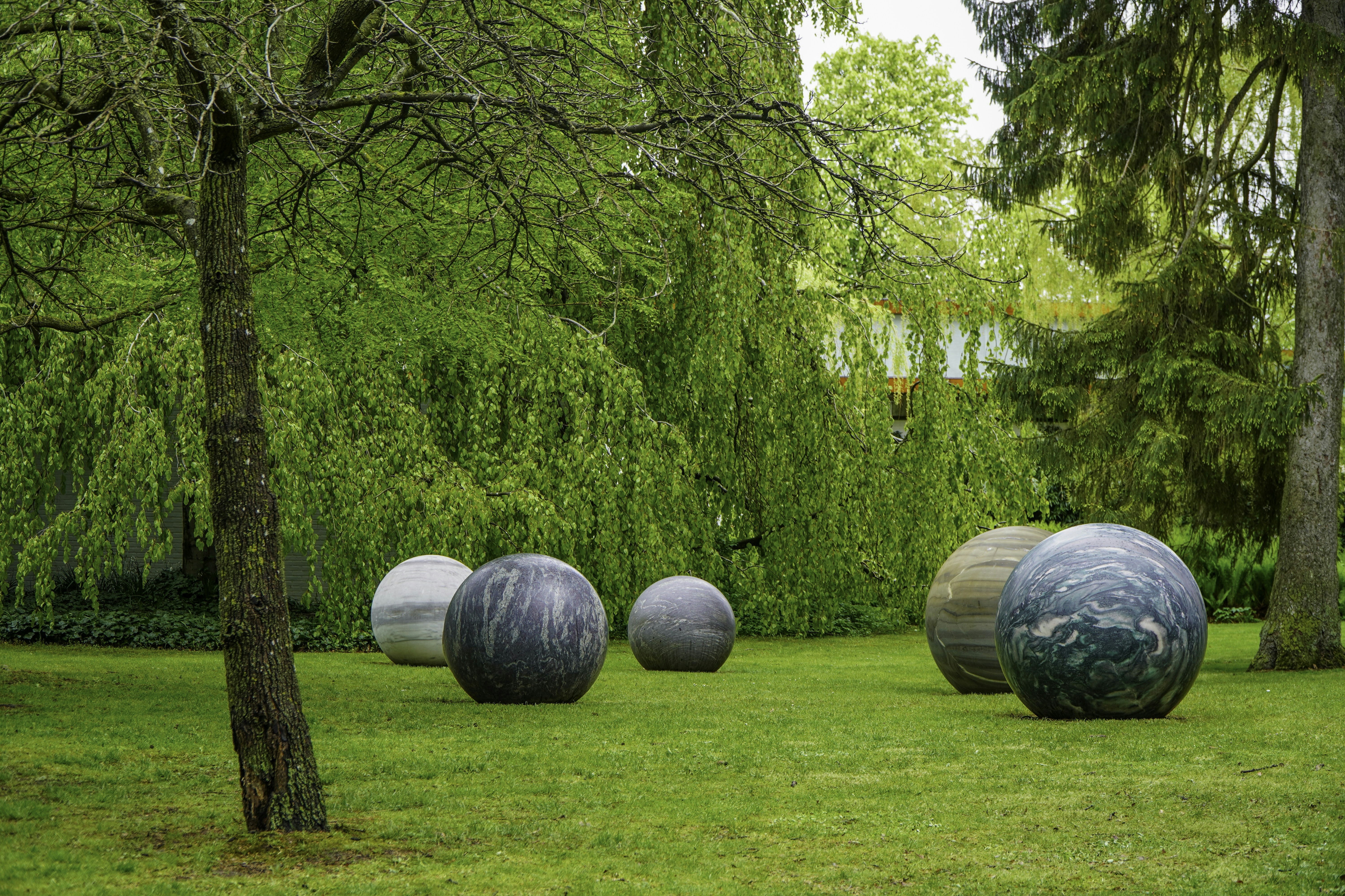 Large spherical sculptures on a green lawn under trees.