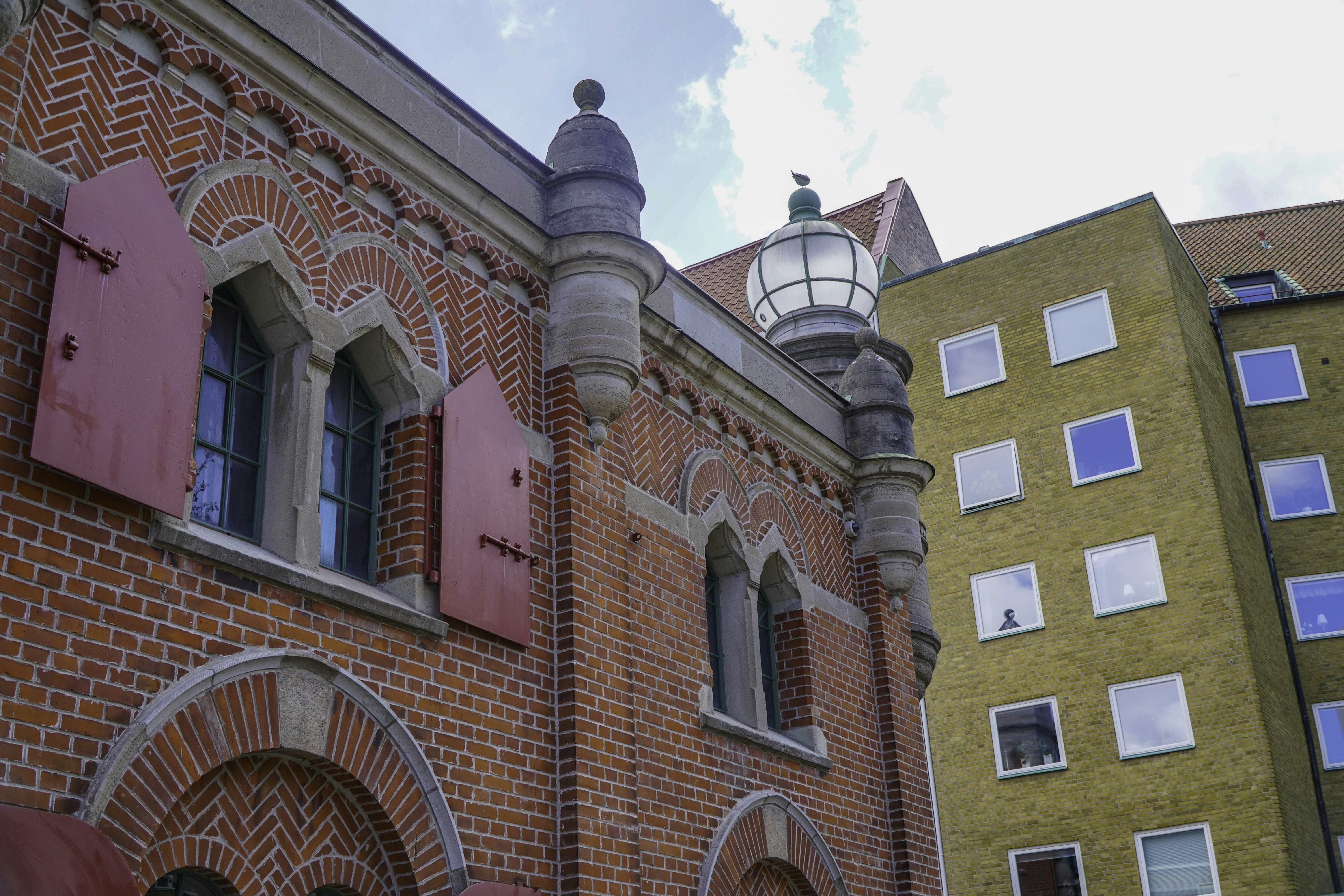 Ornate red brick building and a plain yellow building.
