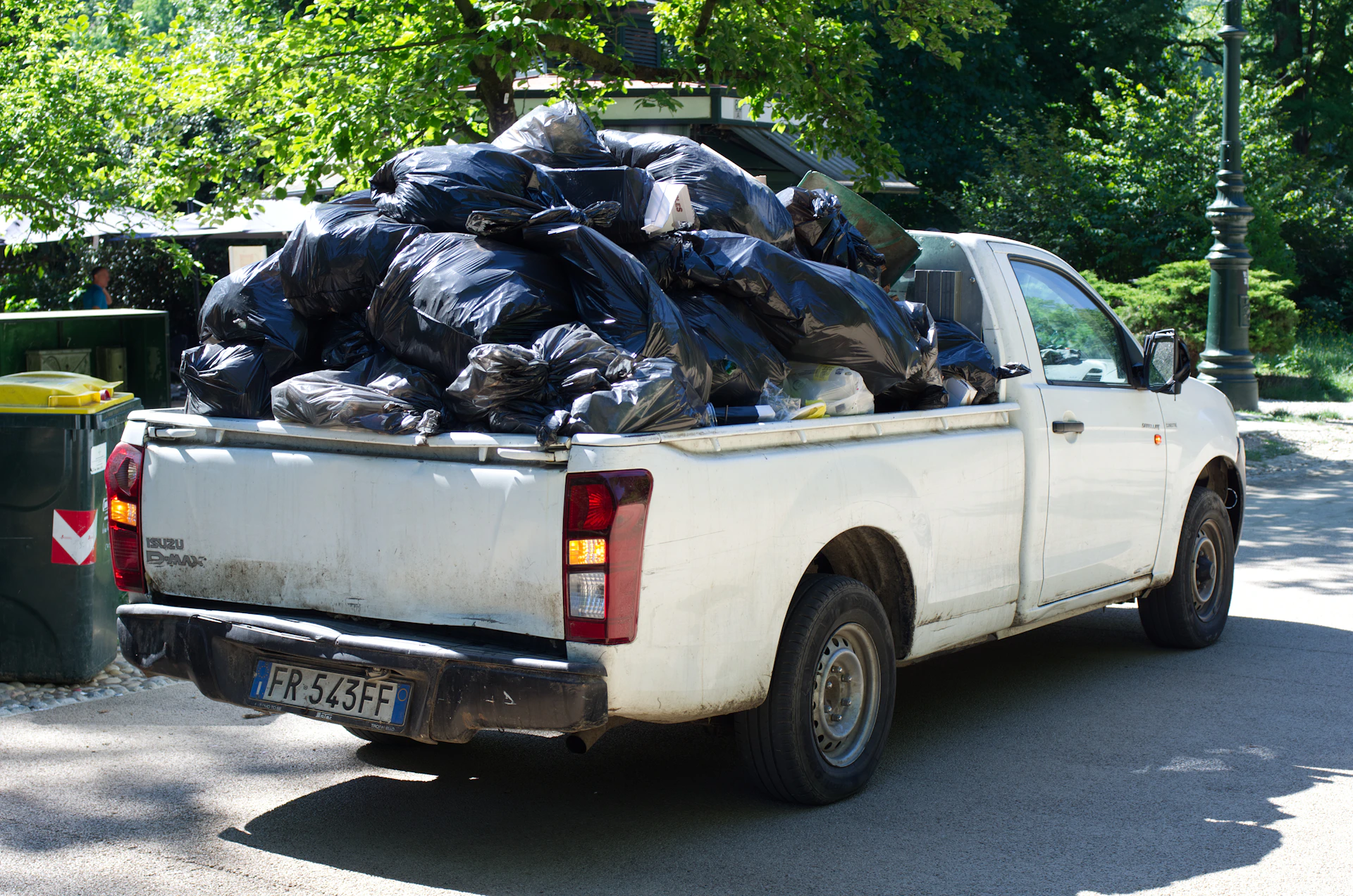 A white pickup truck overloaded with black trash bags.