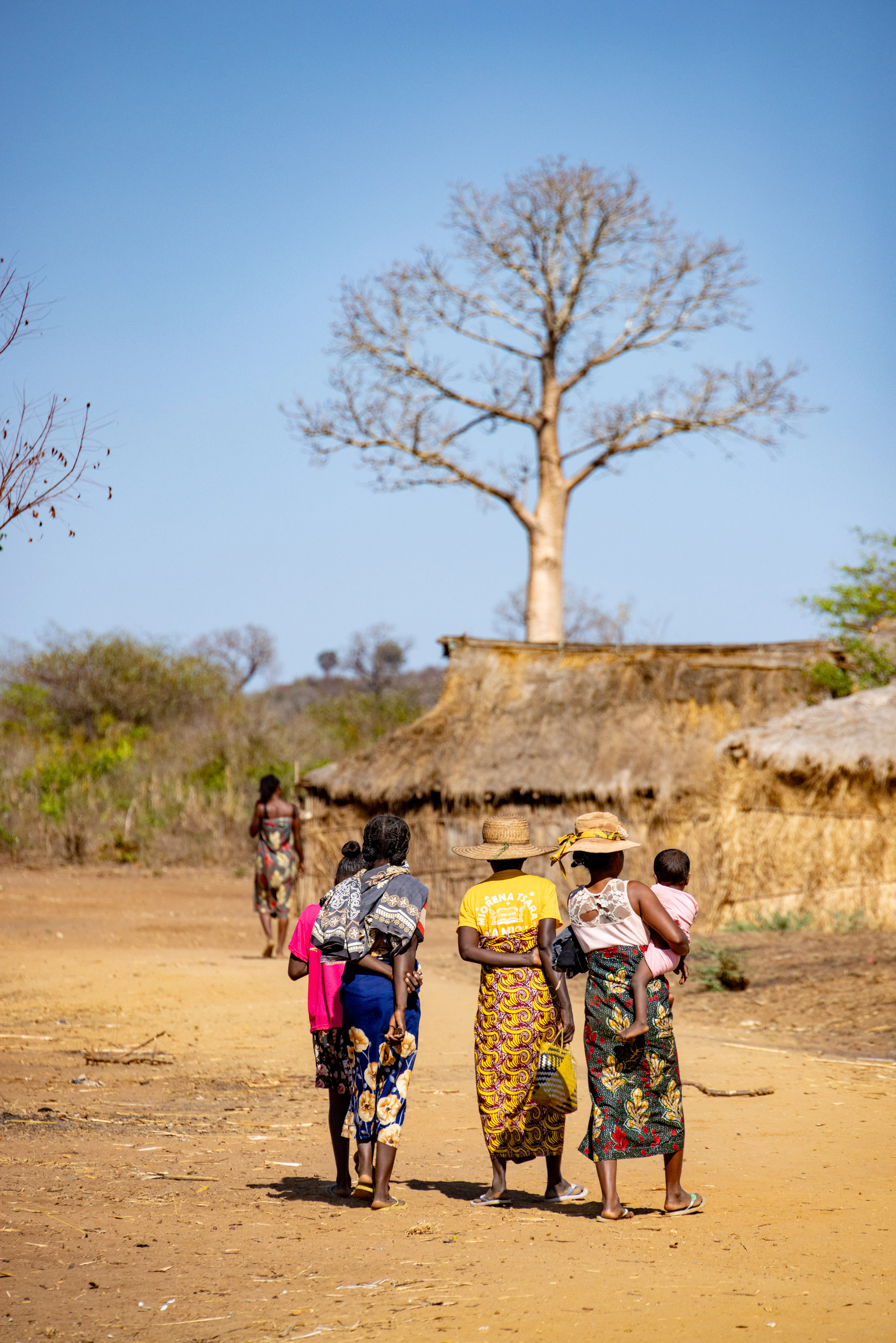Women carrying children through a rural village