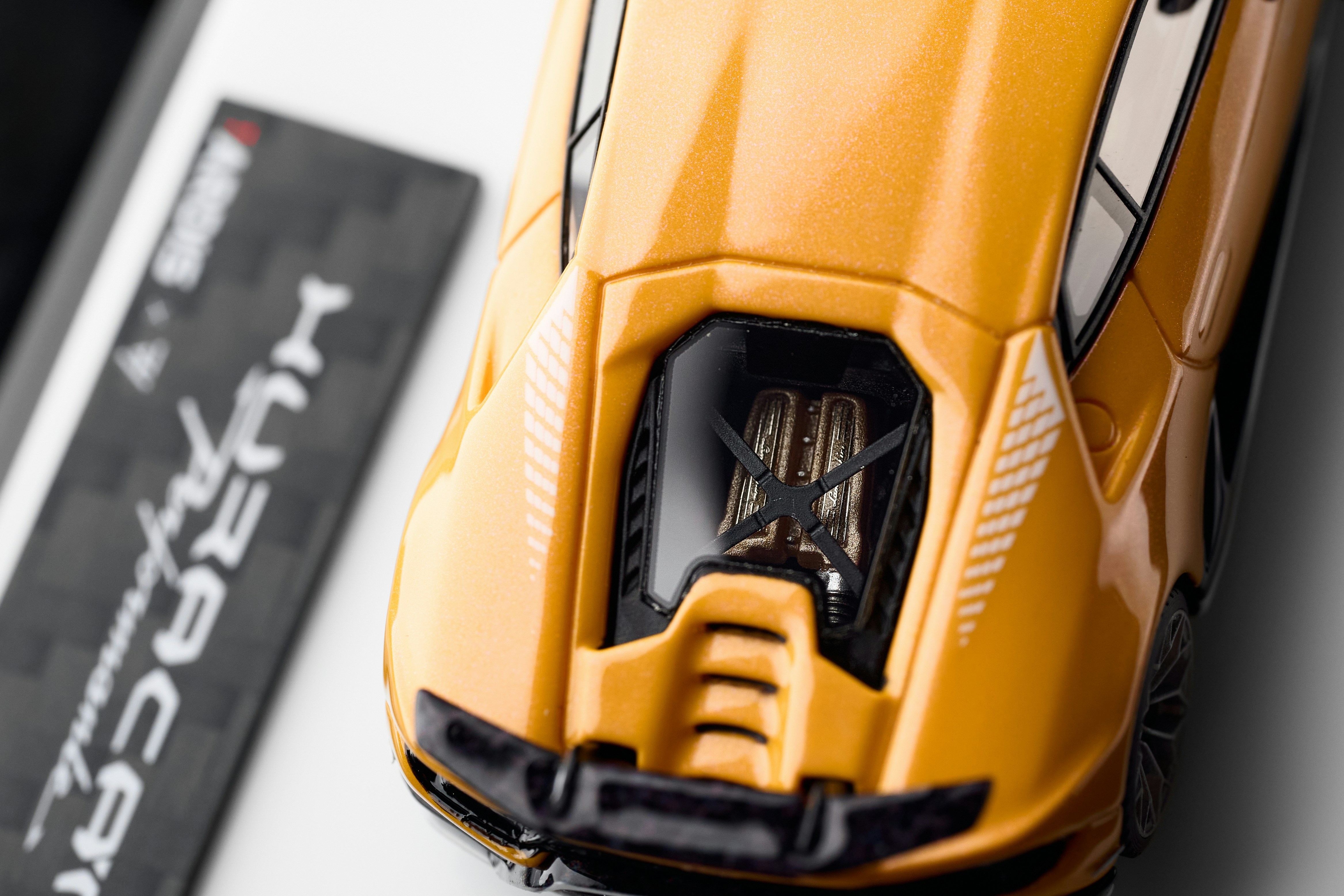 Yellow toy car with engine detail next to its box