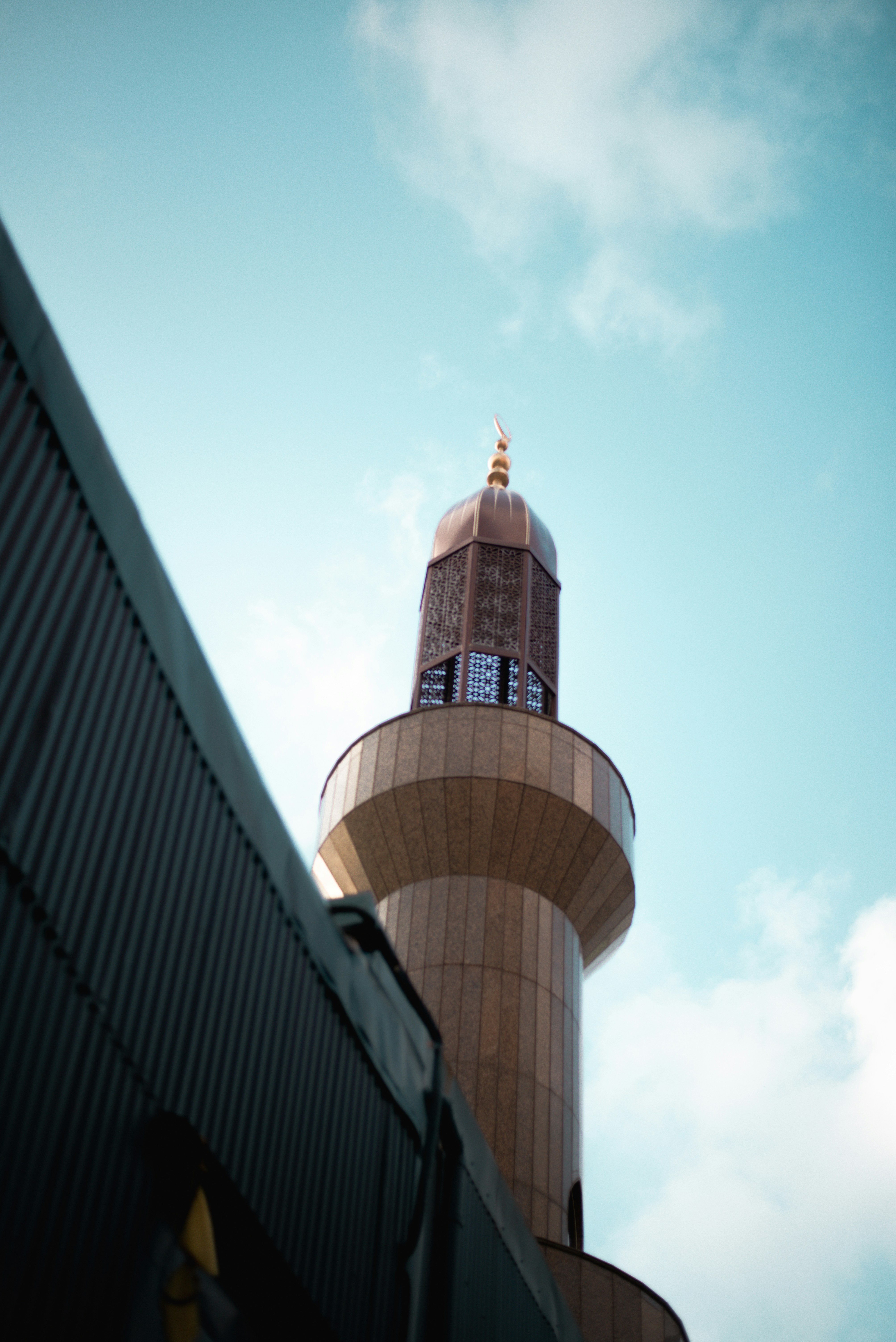 Mosque minaret with golden dome against a blue sky.