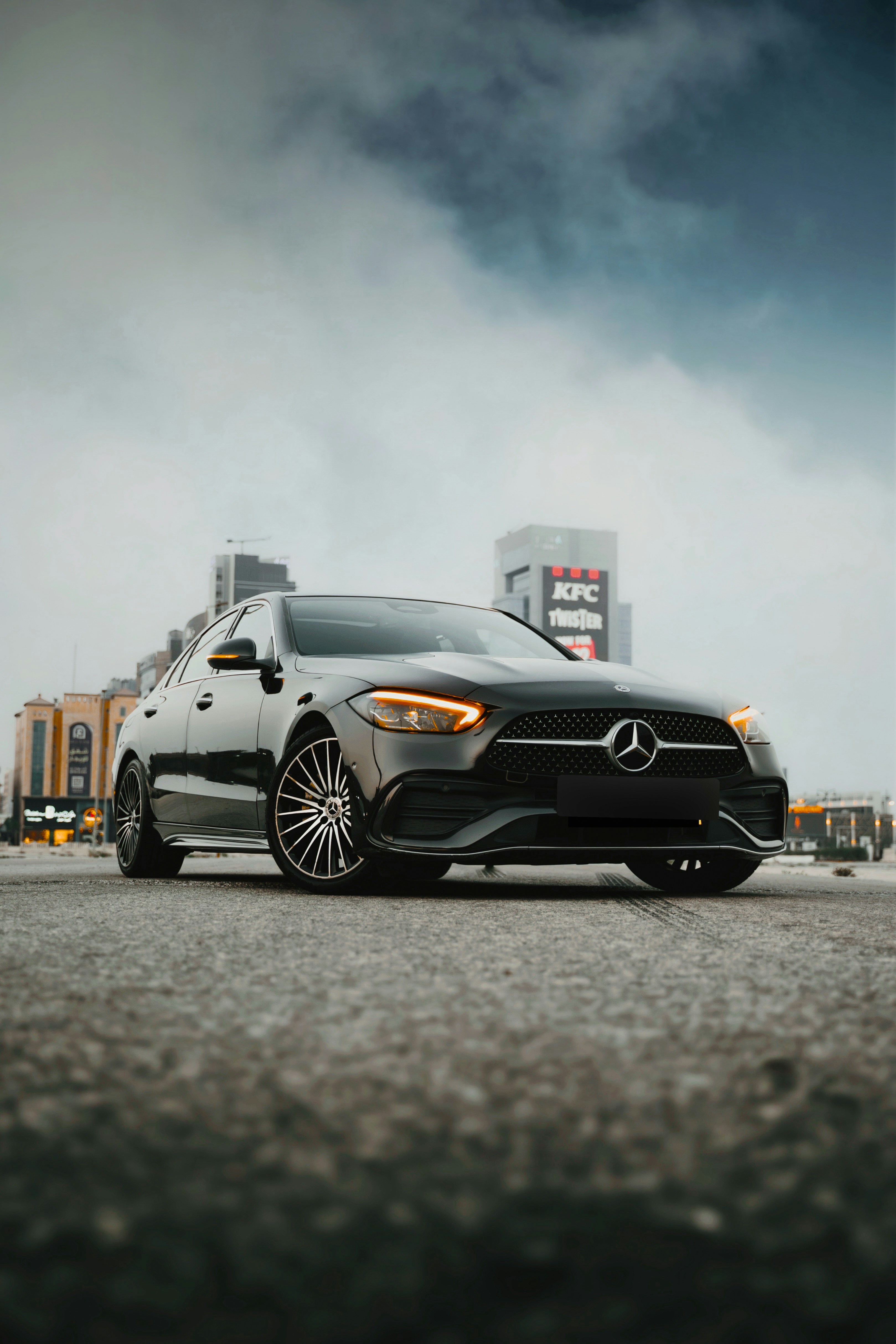 Black mercedes-benz car parked on city street under cloudy sky.