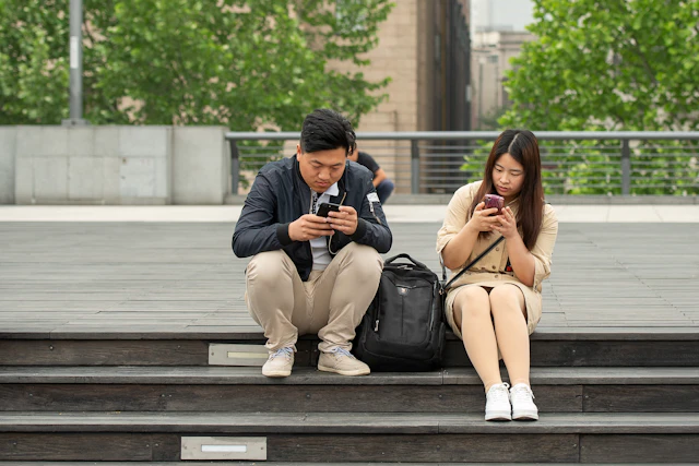 Dos personas concentradas en sus teléfonos y desconectadas de su entorno