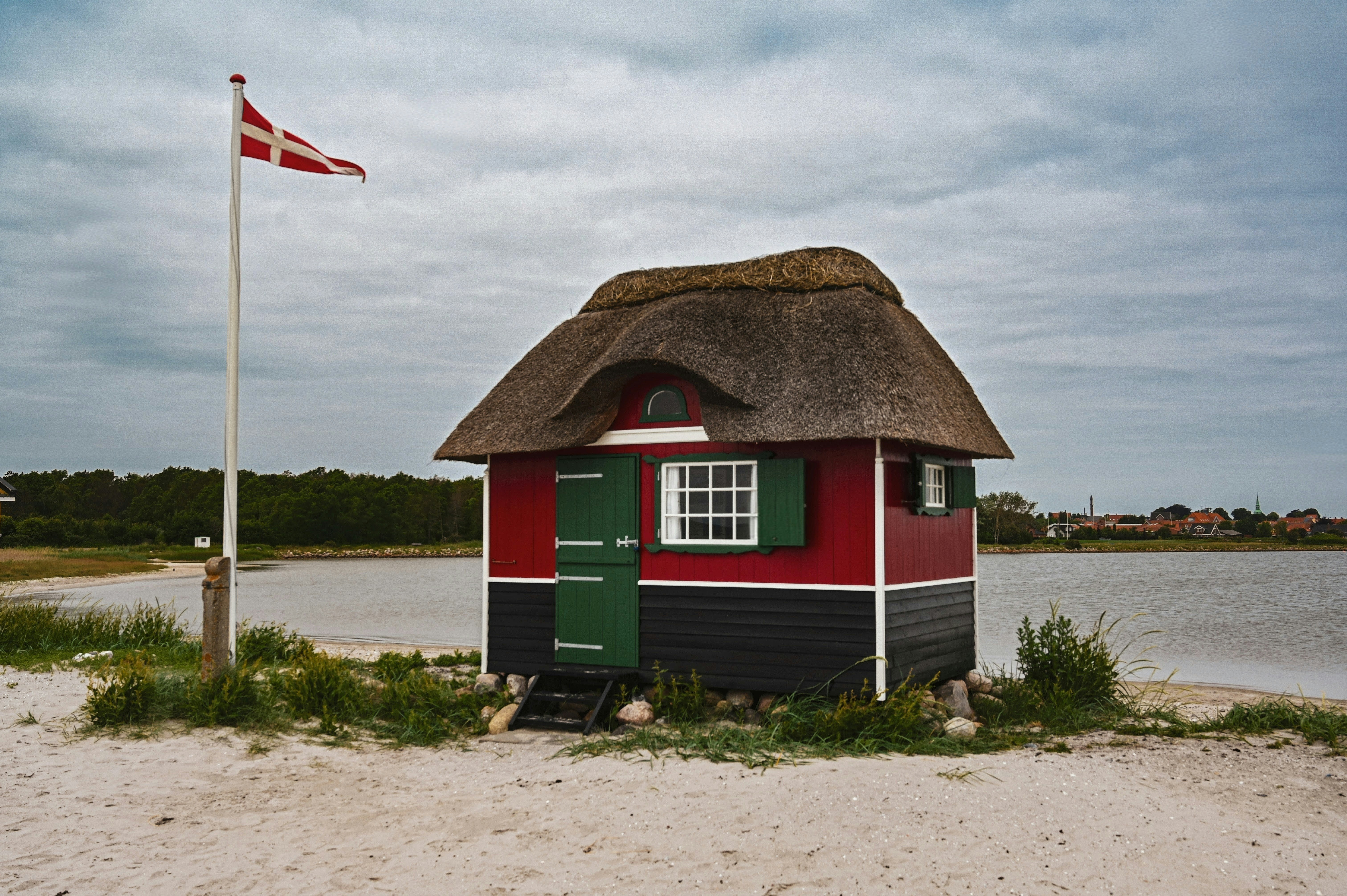 Thatched hut and danish flag on a sandy beach.