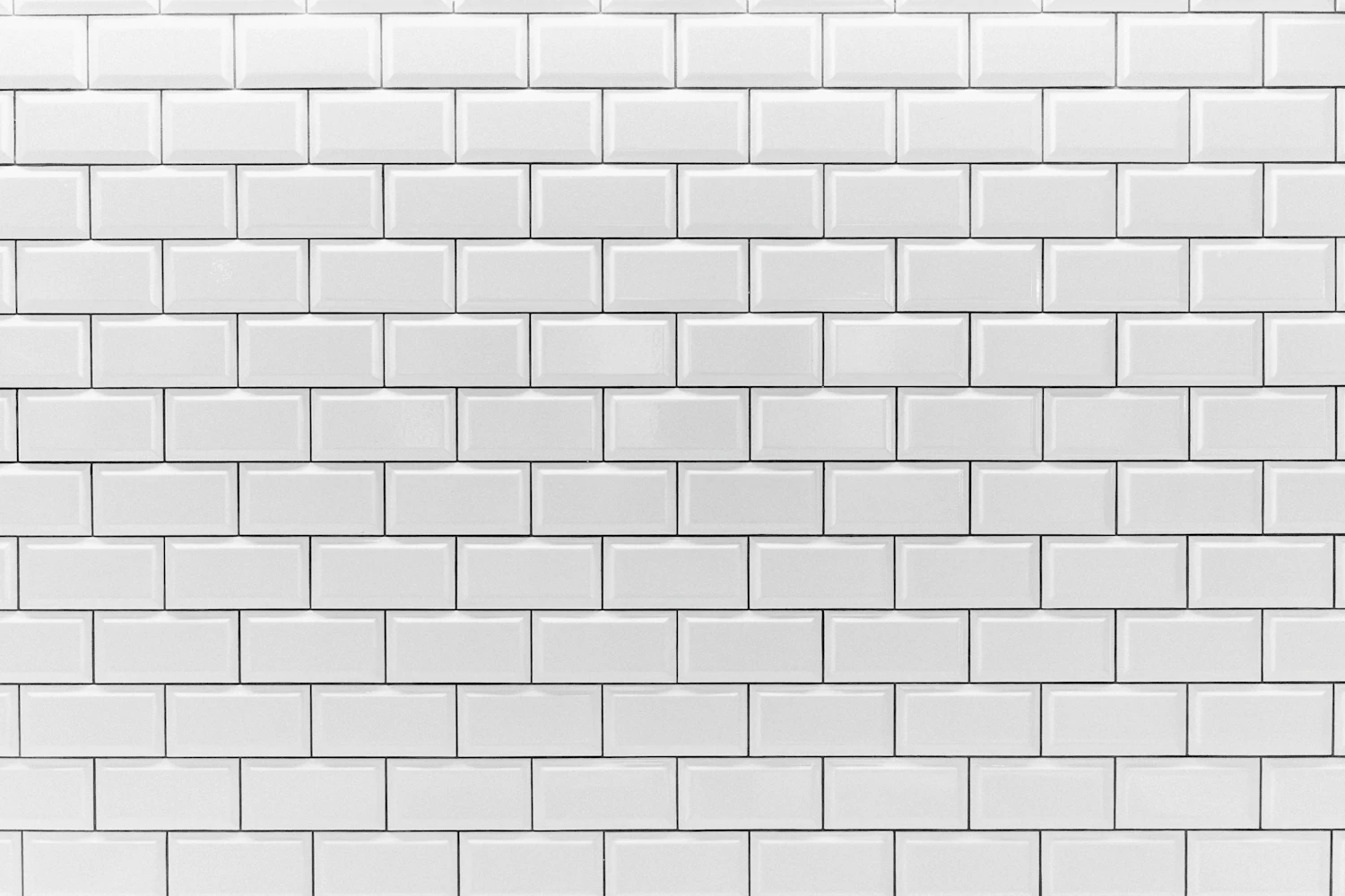 The white subway-tiled wall behind the Gijón bench