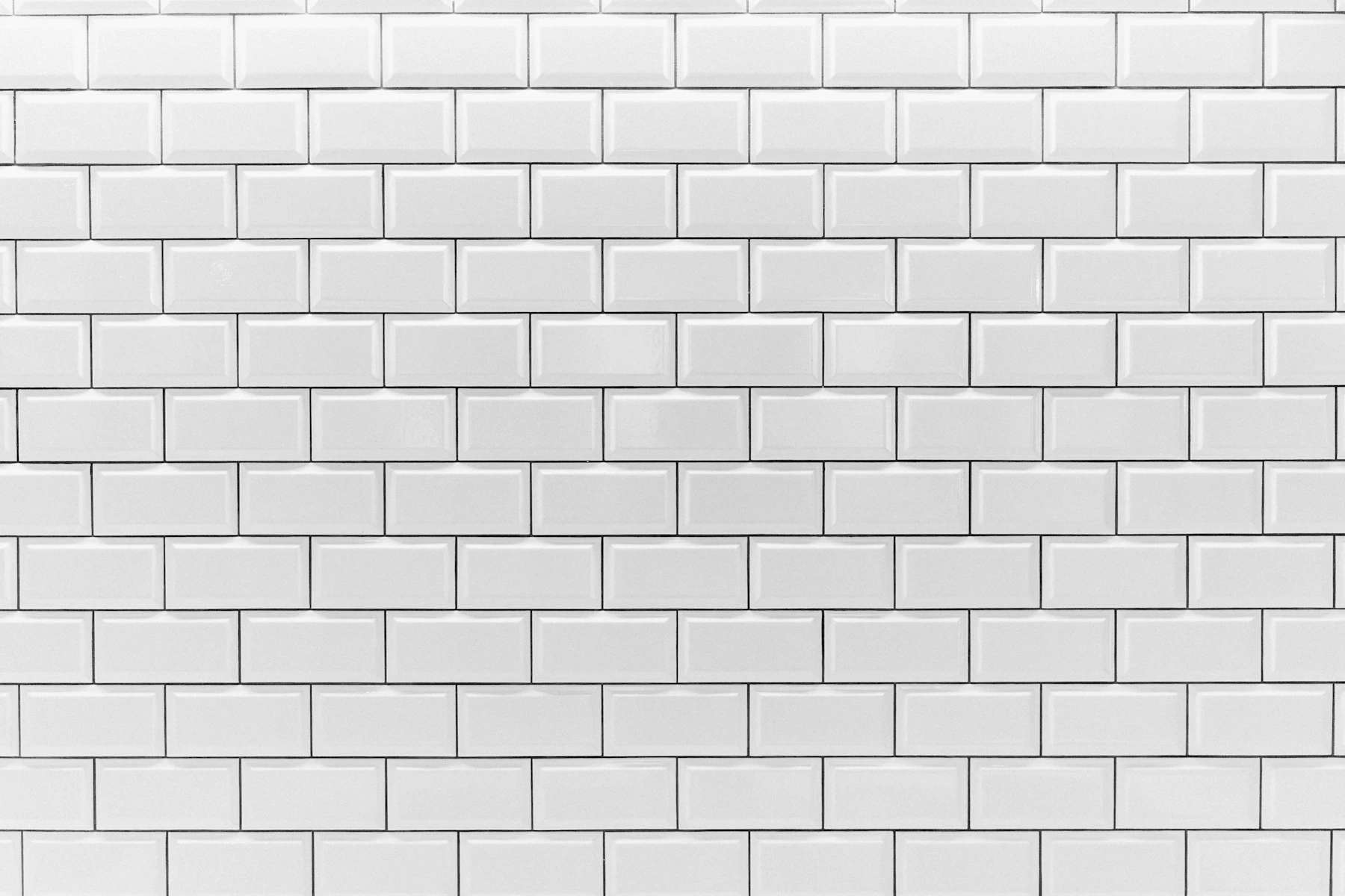 A wall of white glazed subway tile laid in a running bond with gray grout