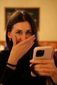 A woman covers her mouth while looking at her phone.