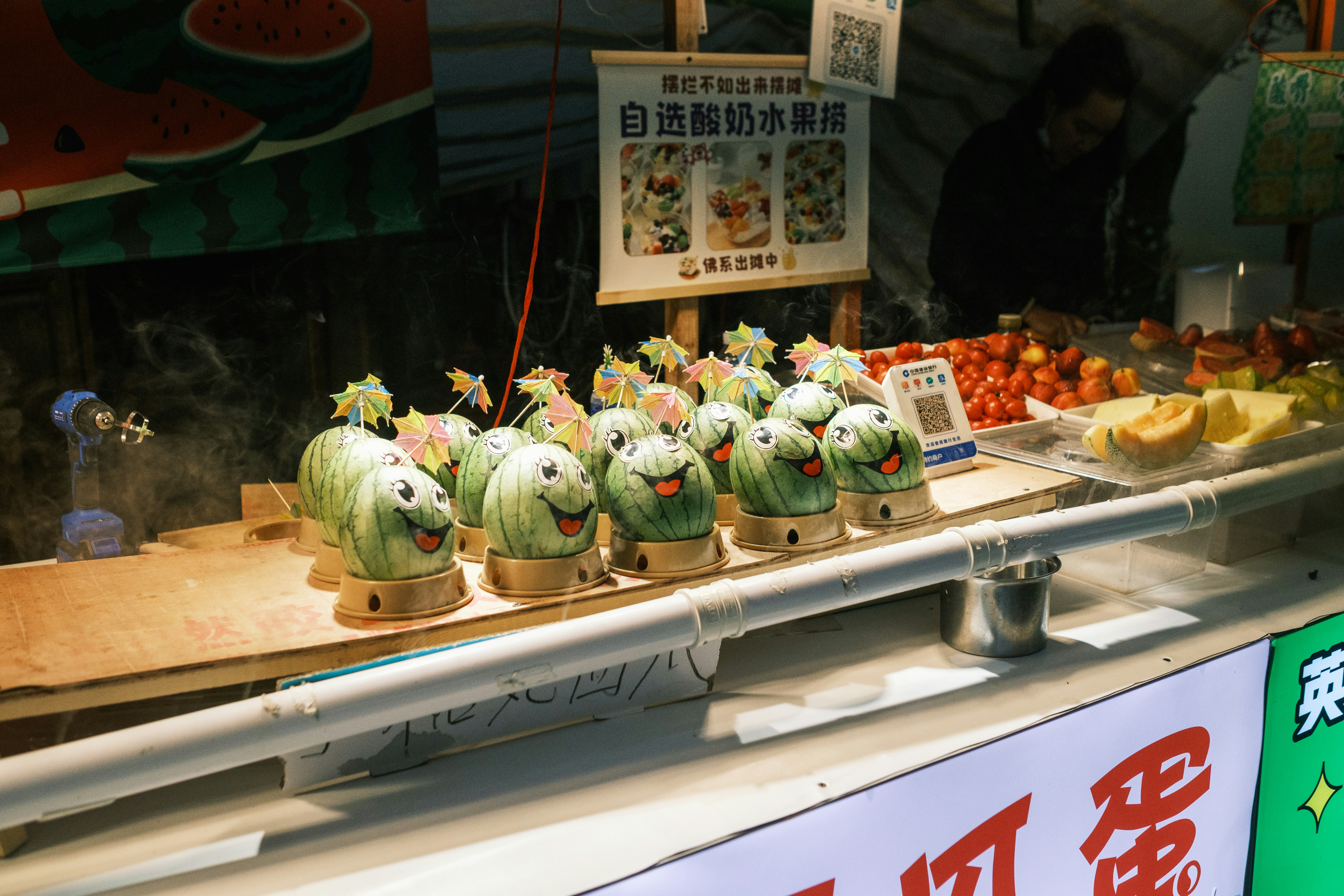 Green cartoon-like desserts displayed at an outdoor food stall.