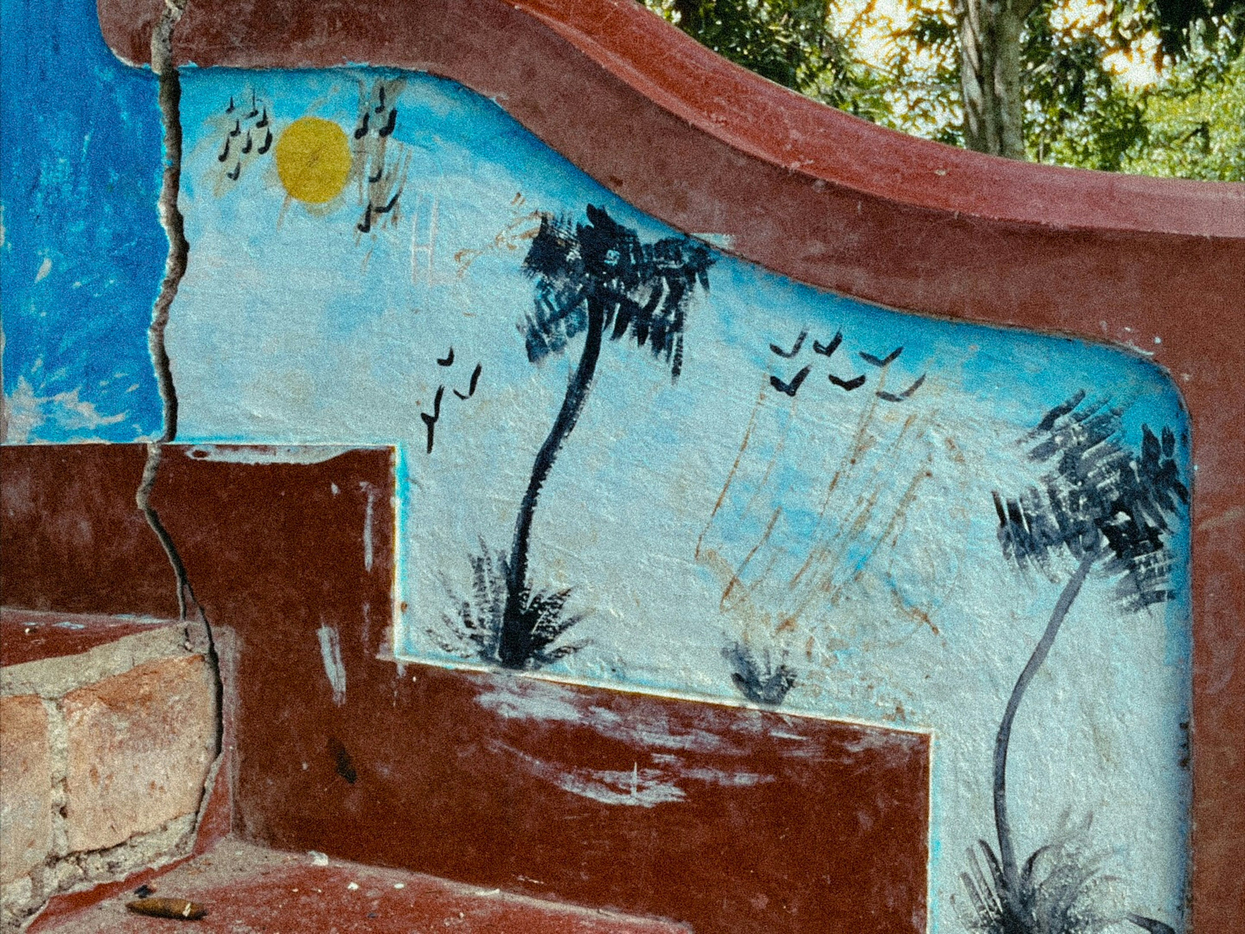 A colorful wall mural depicts palm trees, sun, and birds