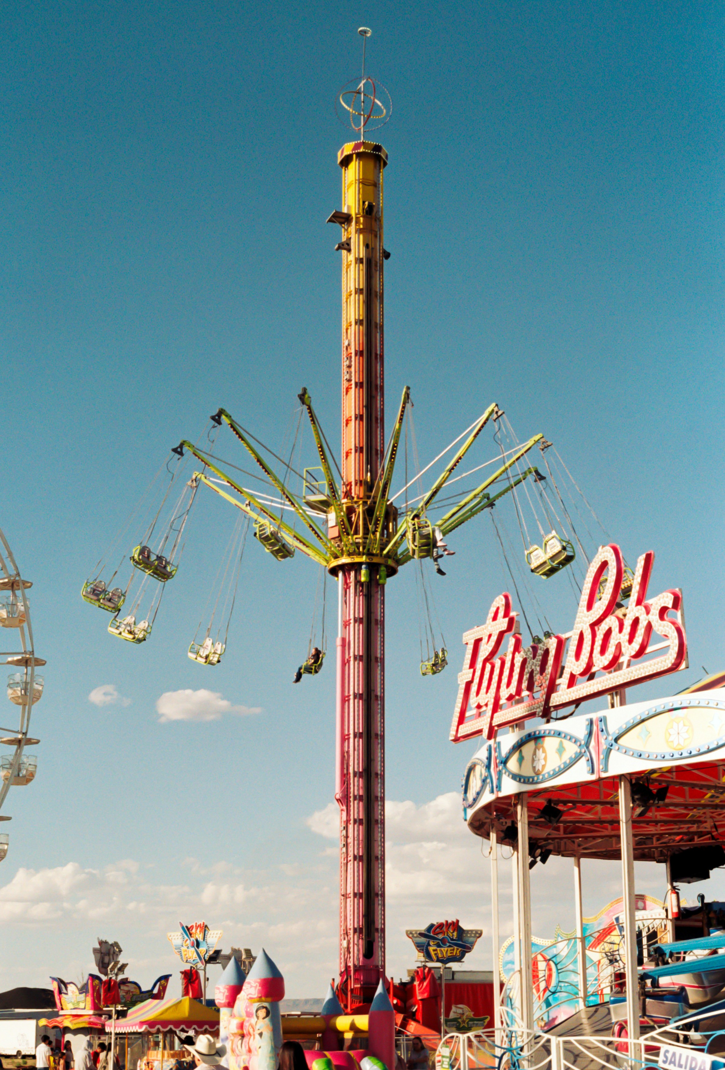 Carnival swing ride and flying bobs attraction under blue sky.