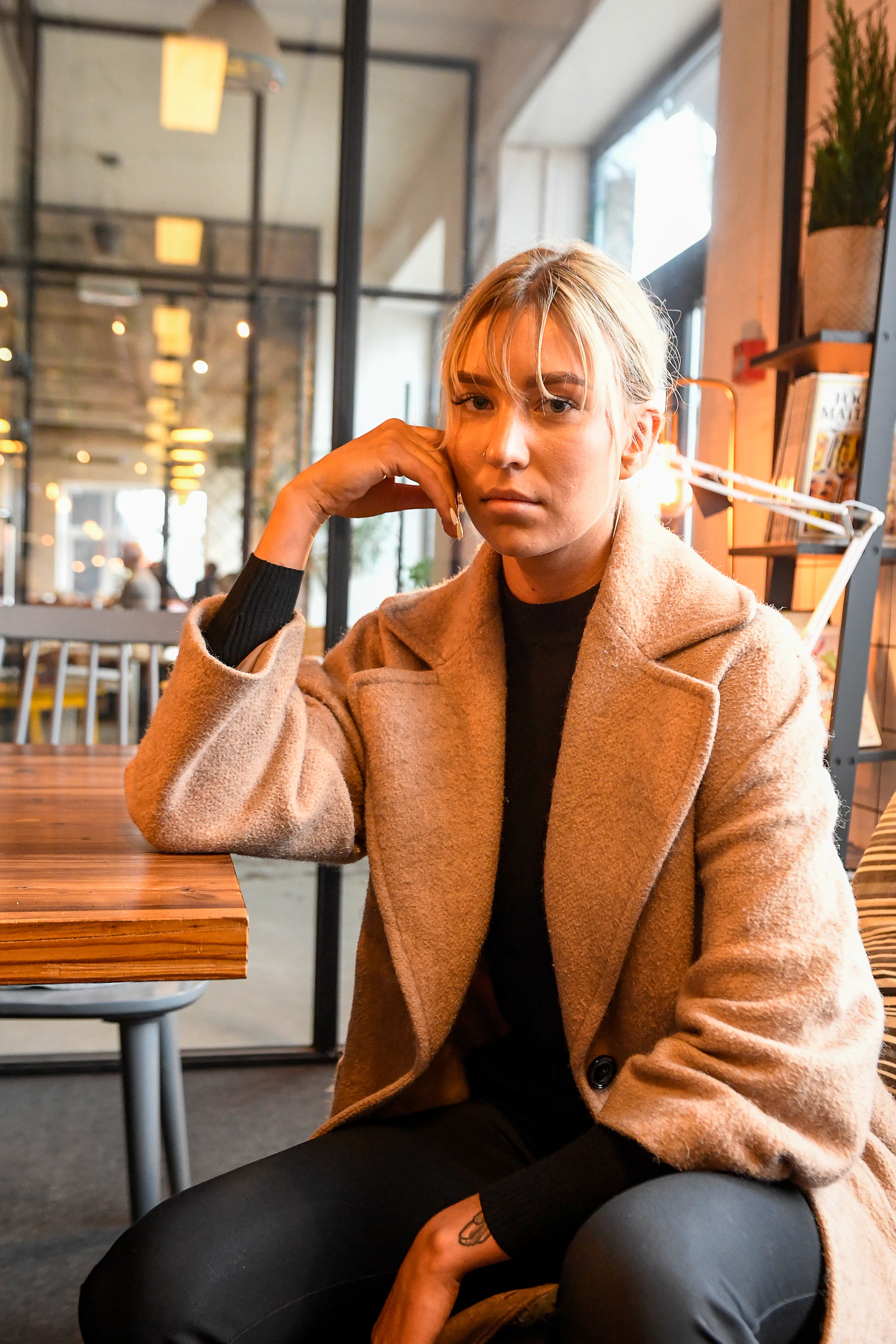 Thoughtful woman sitting alone in a cafe while reflecting on trust after heartbreak