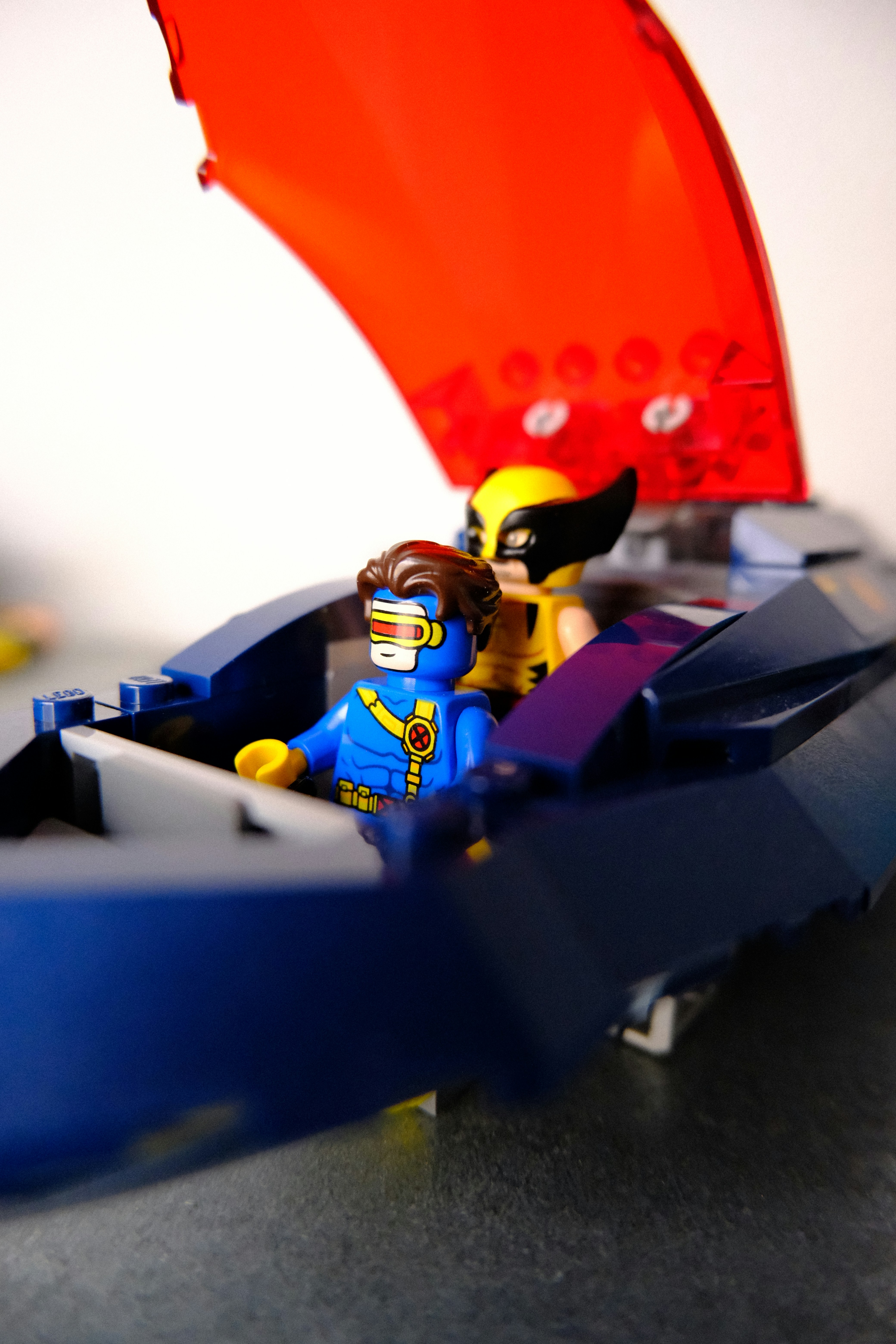 Cyclops and wolverine lego minifigures in a blue vehicle