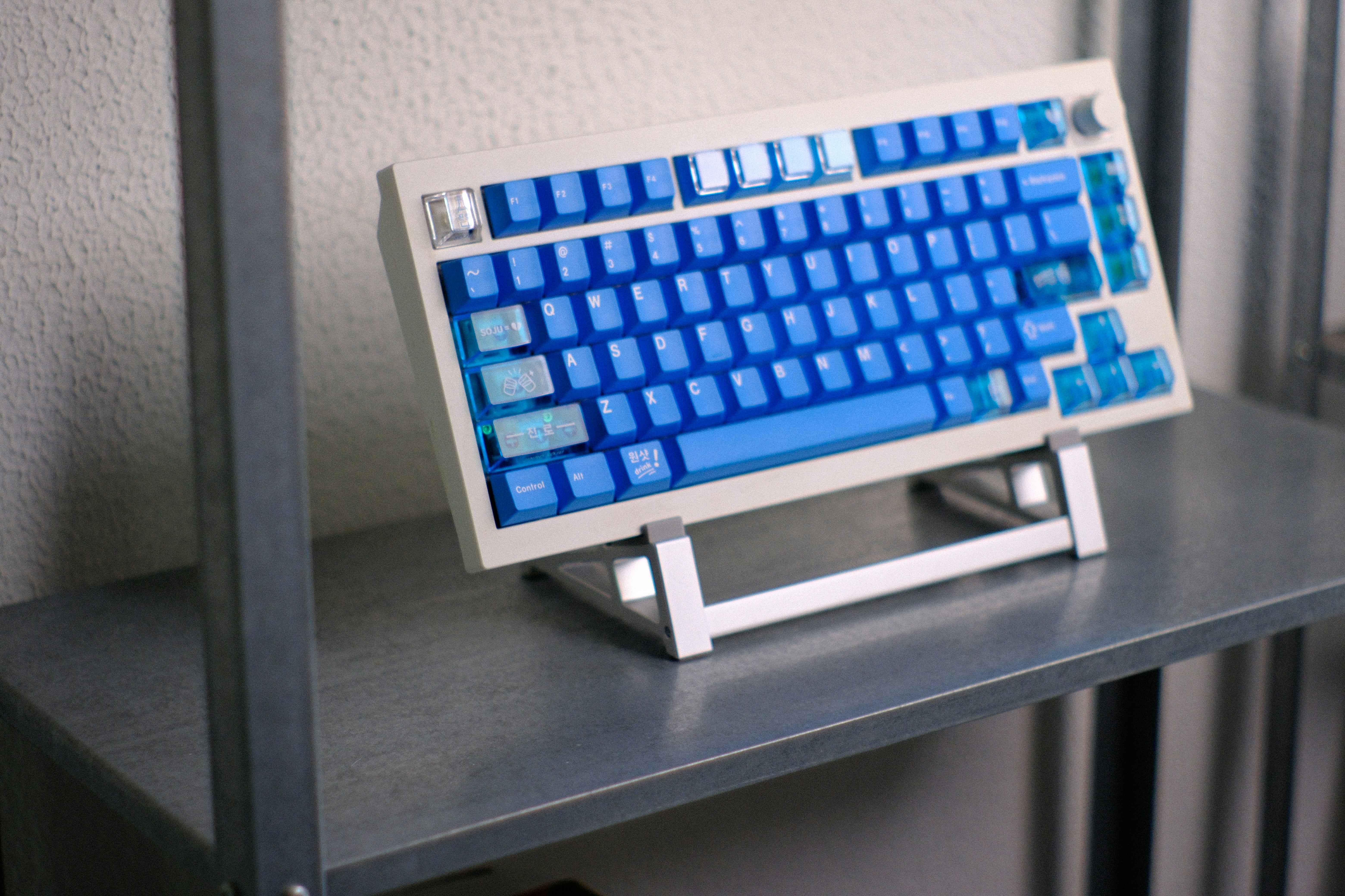A mechanical keyboard with blue keycaps on a metal stand.