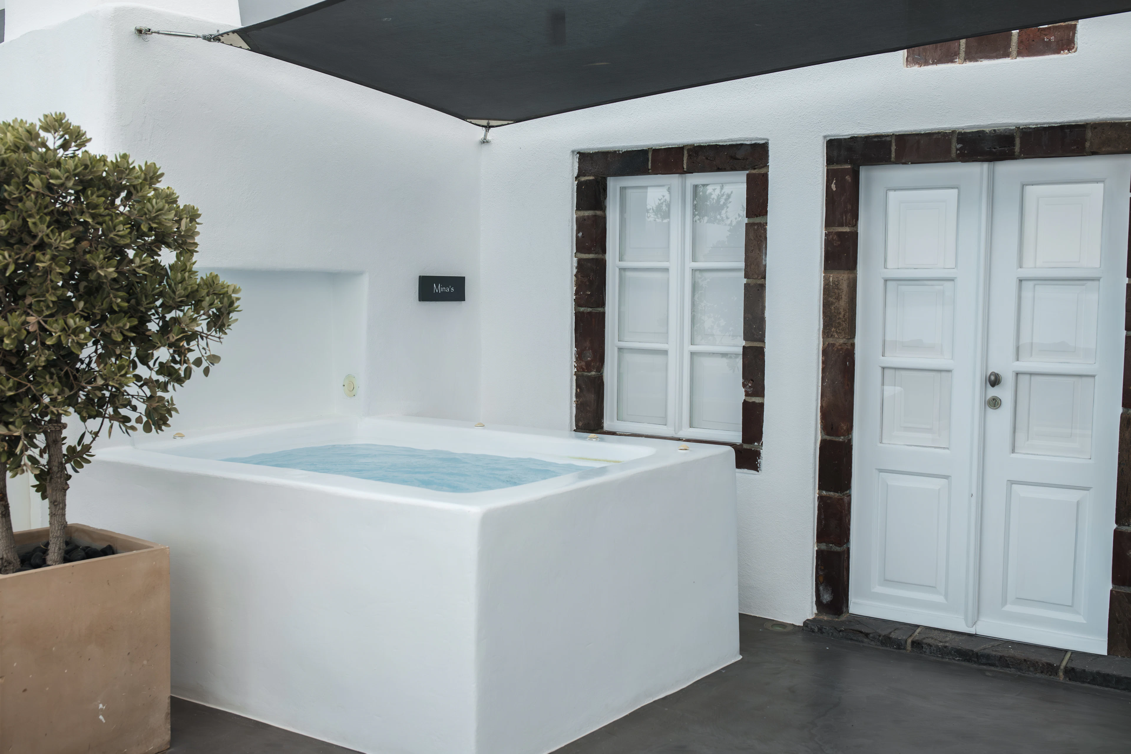 Square hot tub set into a white patio beside a contemporary building