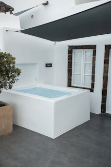 Outdoor white hot tub on a patio with a window.