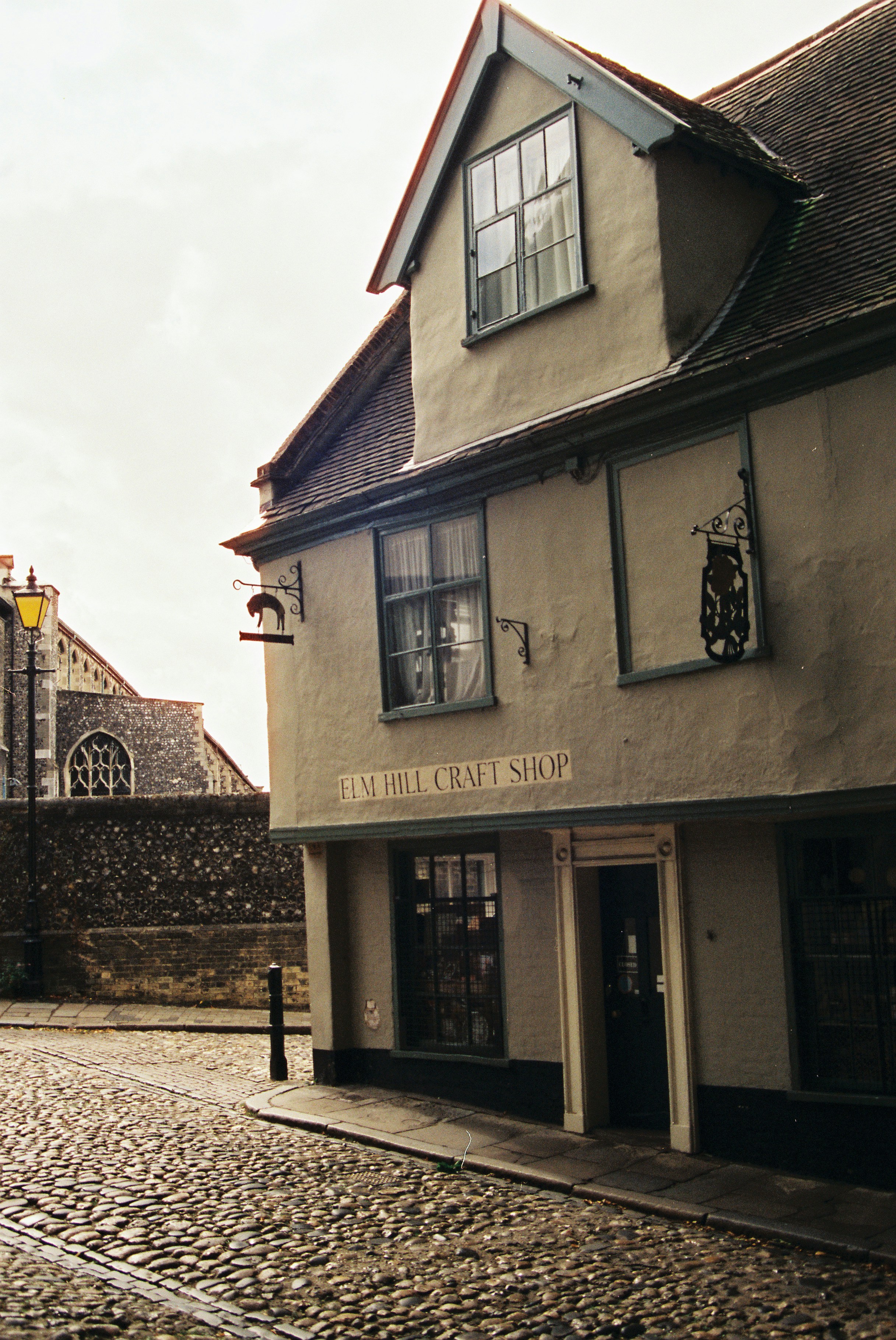 A timber-framed craft shop on a cobbled lane in Norwich under a pale winter sky.