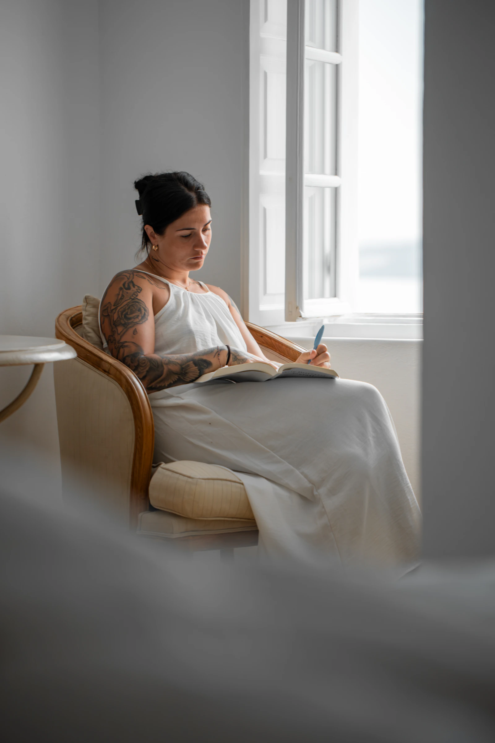 Woman writing privately in a journal by a window after deciding not to send a breakup message