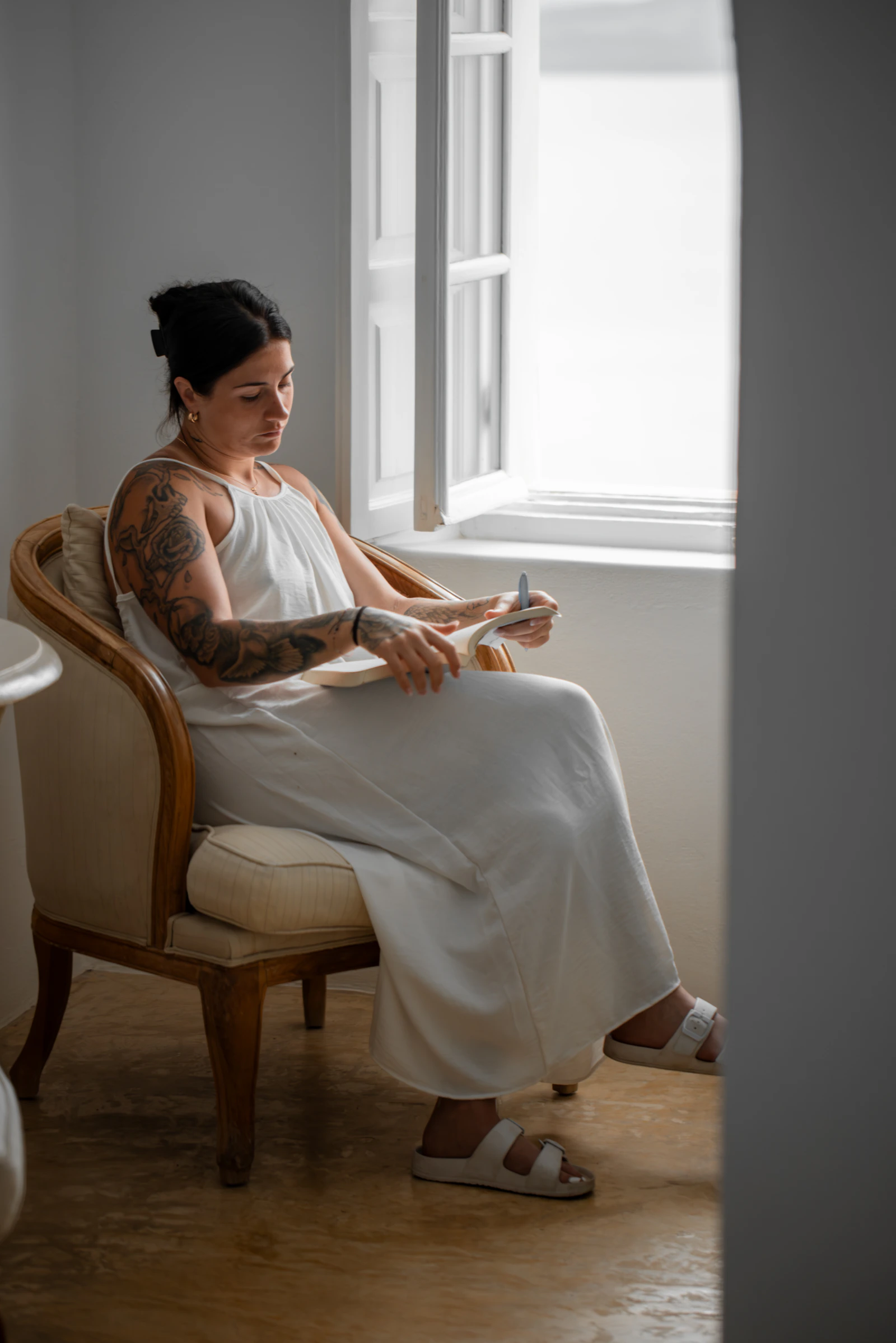 Woman writing quietly beside an open window, representing reflection without reopening contact after a breakup