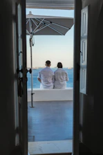 Open door frames two people enjoying ocean view.