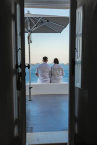Open door frames two people enjoying ocean view.