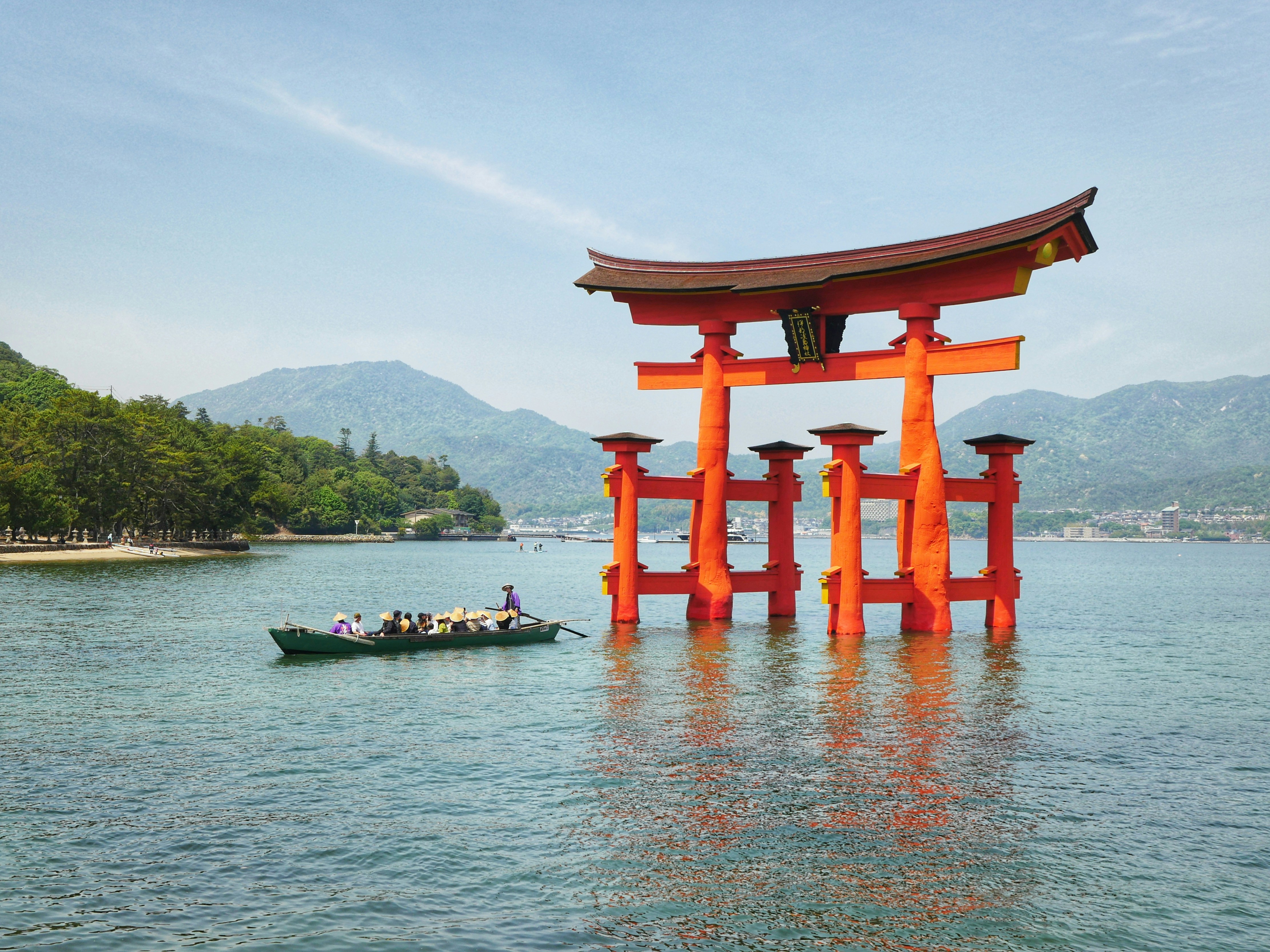 Célèbre porte torii rouge dans l’eau avec un petit bateau.